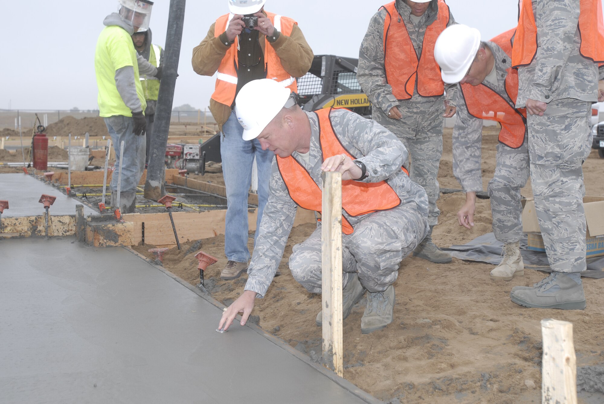 Col. Jay Raymond, 21st Space Wing commander, inserts the official 21st SW coin  into the first new Tierra Vista Home foundation on Peterson Air Forec Base, Oct. 20. This foundation pouring marked the beginning of phase one of new construction on the privatized housing development. This initial phase will include 93 homes. (Air Force photo/Larry Hulst)
