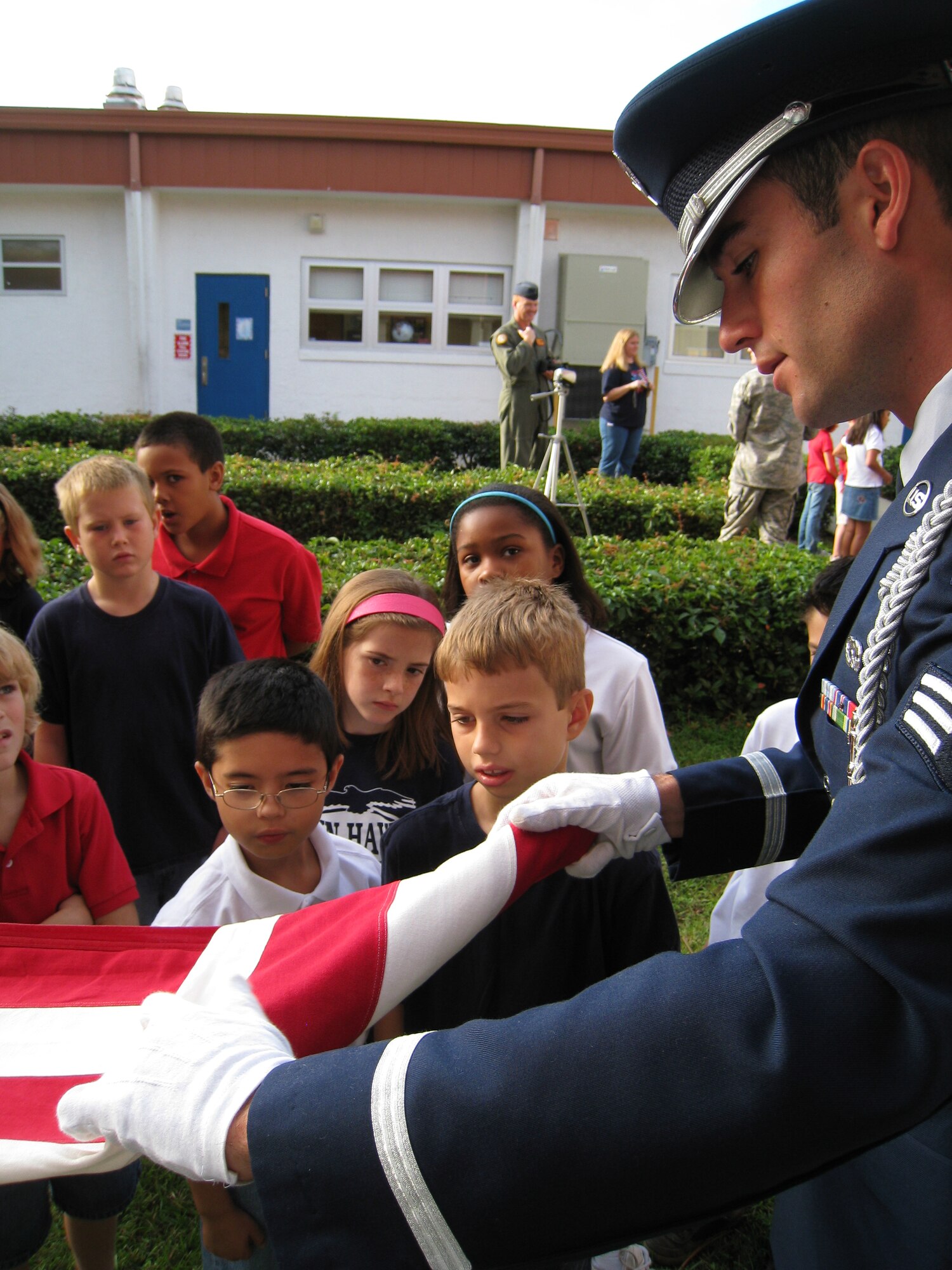 Lynn Haven Elementary students look on as Senior Airman Brendan Crawford, a Tyndall Air Force Base Honor Guard member, demonstrates how to properly fold the American flag.  The third graders from Mrs. Amy Harvey’s class, who are responsible for raising and lowering the flag each school day, were instructed on flag etiquette by the Honor Guard Tuesday.  (U.S. Air Force photo by:  Maj. Veronica Kemeny)  