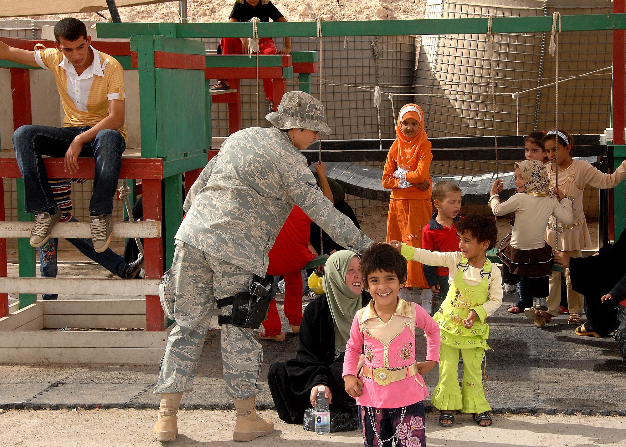 A security forces member from the 586th Air Expeditionary Group plays with Iraqi children at Camp Bucca, Iraq, while they wait for transport to the detainee visitation center recently. The 586th AEG provides security and transport to the center for nearly 400 visitors who are allowed to visit daily with detainees being held at the theater internment facility. (U.S. Air Force photo/Tech. Sgt. Raheem Moore)