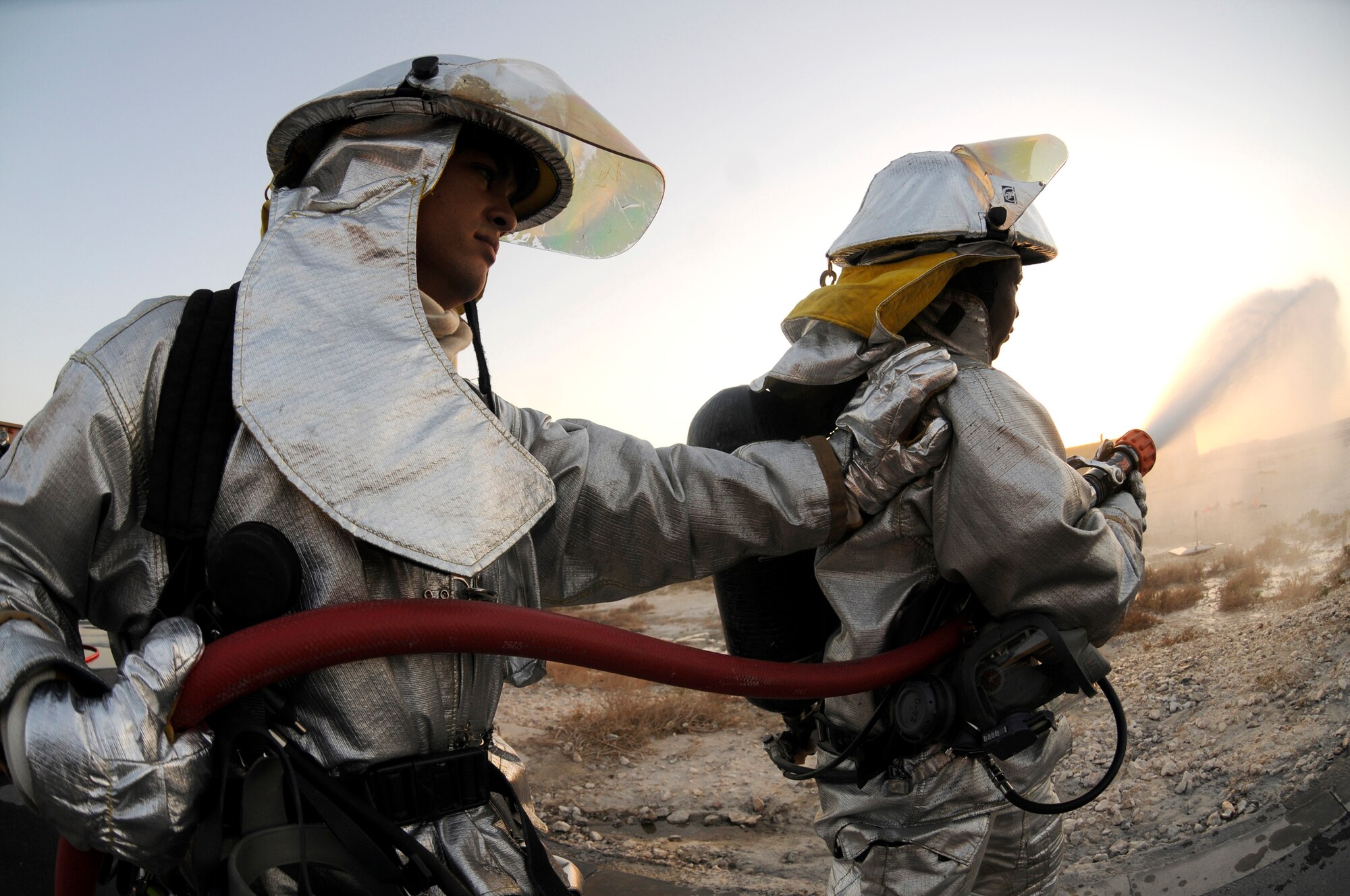 Staff Sgt. Alex Retamoza uses his hand to support Airman 1st Class Michael Thomas as he sprays a hose line as part of a daily operational check Oct. 20, 2008, at an undisclosed air base in Southwest Asia.  Both firefighters are deployed to the 379th Expeditionary Civil Engineer Squadron in support of Operations Iraqi and Enduring Freedom and Joint Task Force-Horn of Africa.  Sergeant Retamoza, a native of South El Monte, Calif., is deployed from Beale Air Force Base, Calif., and Airman Thomas, a native of Union City, Tenn., is deployed from Moody AFB, Ga.  (U.S. Air Force photo by Staff Sgt. Darnell T. Cannady/Released)
