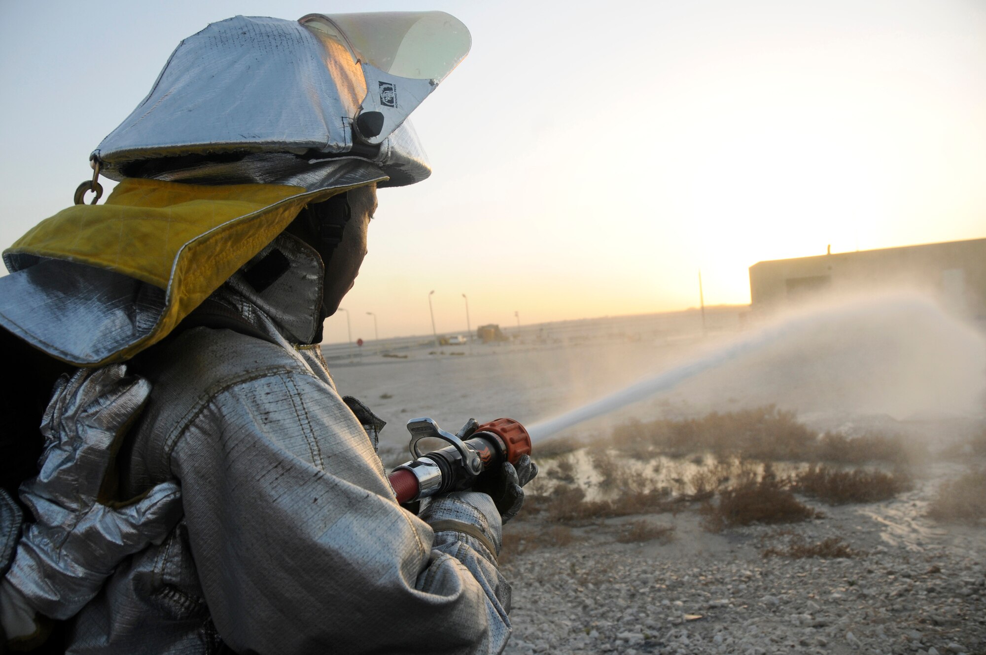 Staff Sgt. Alex Retamoza uses his hand to support Airman 1st Class Michael Thomas as he sprays a hose line as part of a daily operational check Oct. 20, 2008, at an undisclosed air base in Southwest Asia.  Both firefighters are deployed to the 379th Expeditionary Civil Engineer Squadron in support of Operations Iraqi and Enduring Freedom and Joint Task Force-Horn of Africa.  Sergeant Retamoza, a native of South El Monte, Calif., is deployed from Beale Air Force Base, Calif., and Airman Thomas, a native of Union City, Tenn., is deployed from Moody AFB, Ga.  (U.S. Air Force photo by Staff Sgt. Darnell T. Cannady/Released)