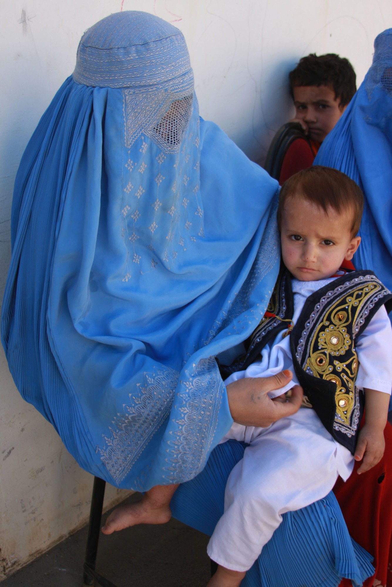 BAGRAM AIR FIELD, Afghanistan – An Afghan mother, veiled by a burqa, holds her son on her lap as they wait to be seen at the Obdara clinic, where PRT Panjshir medical personnel assisted a local midwife and nurse on Oct. 16. 

