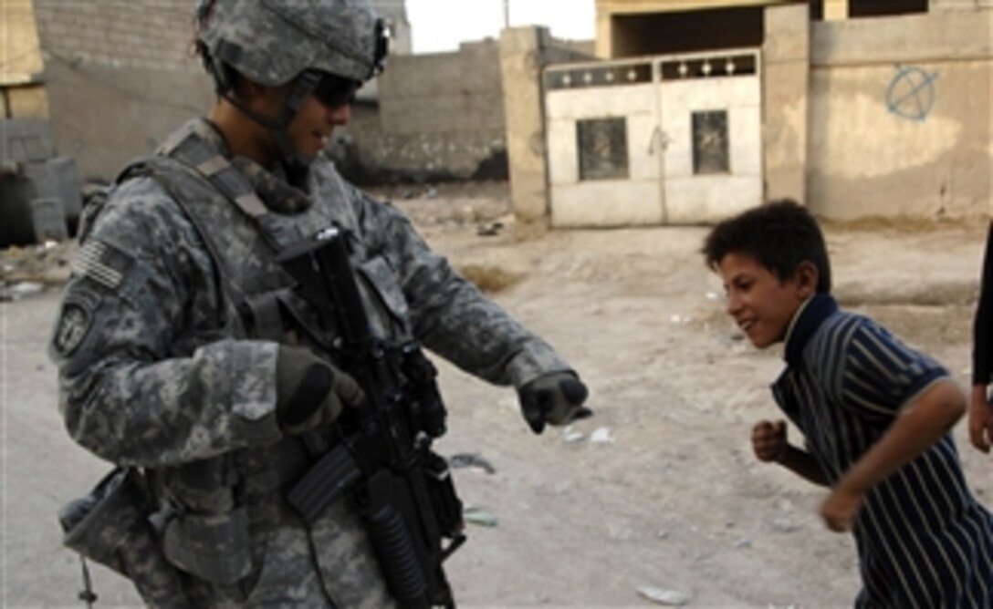 U.S. Army Lt. Caldwell, from 21st Military Police Company (Airborne), Multi-National Division-Southeast, gets a fist bump from a young Iraqi boy while on patrol outside the Al Quibla Iraqi Police station in Barsa, Iraq, on Oct. 2, 2008.  