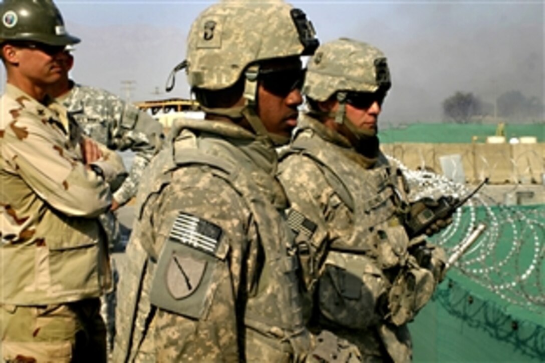 U.S. Army Spc. Quincy Lendo, center, and Sgt. 1st Class Jason Blunck, right, along with other servicemembers, observe a burning field on Bagram Air Field, Afghanistan, Oct. 21, 2008.  Both soldiers are members of the Illinois National Guard, assigned to the Explosive Hazardous Coordination Cell at Bagram. The field was burned to allow de-mining operations to begin in the area and to clean out a creek vital to two local villages.