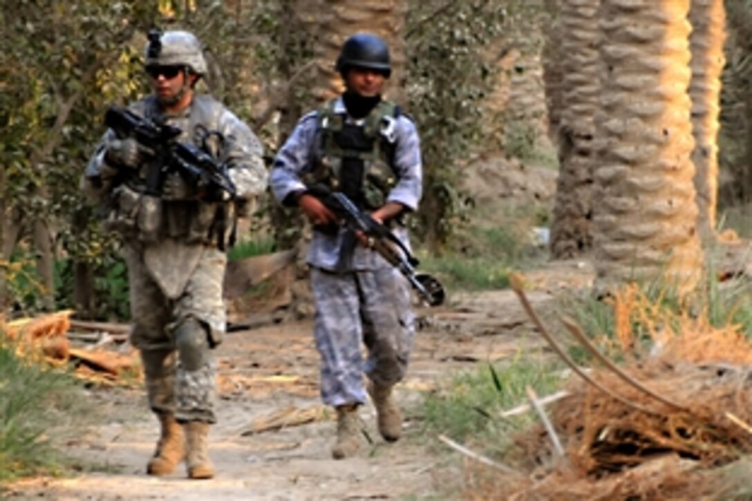 U.S. Army Staff Sgt. Kelley Martin (left), and an Iraqi police walk through a date palm grove during a patrol in Diwaniya, Iraq, Oct. 14, 2008. Martin is a tank commander,  assigned to Company C, 2nd Combined Arms Battalion, 8th Infantry Regiment, 2nd Brigade Combat Team, 4th Infantry Division.