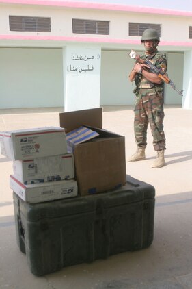 An Iraqi soldier stands guard near a box of school supplies at an elementary school in Khasfah, Iraq, Oct. 21. The Iraqi Army distributed school supplies to the students and teachers to help them improve their relationship with the people of Khasfah, which is one of the many rural towns they are now responsible for the security of.  Since security of al-Anbar province has been given back to the Iraqi government, the IA has started playing a bigger role in operations as the Marines with the Baghdadi Military in Transition Team have stepped back and supervised.