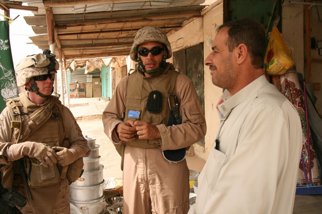 Assisted by his Bashar Basem Radi Ayesh (center), an interpreter from Amman Jordan, Navy Cmdr. Dennis McKenna (left), the battalion surgeon and economic line of operations officer with 2nd Battalion, 25th Marine Regiment, Regimental Combat Team 5, speaks with a shop owner in Rutbah, Iraq, Oct. 21 in order to assess the economic conditions for small business owners.  Rutbah, a town of about 20,000 in Iraqâ??s western al-Anbar Province, is the largest population center in the battalion's area of responsibility. ::r::::n::