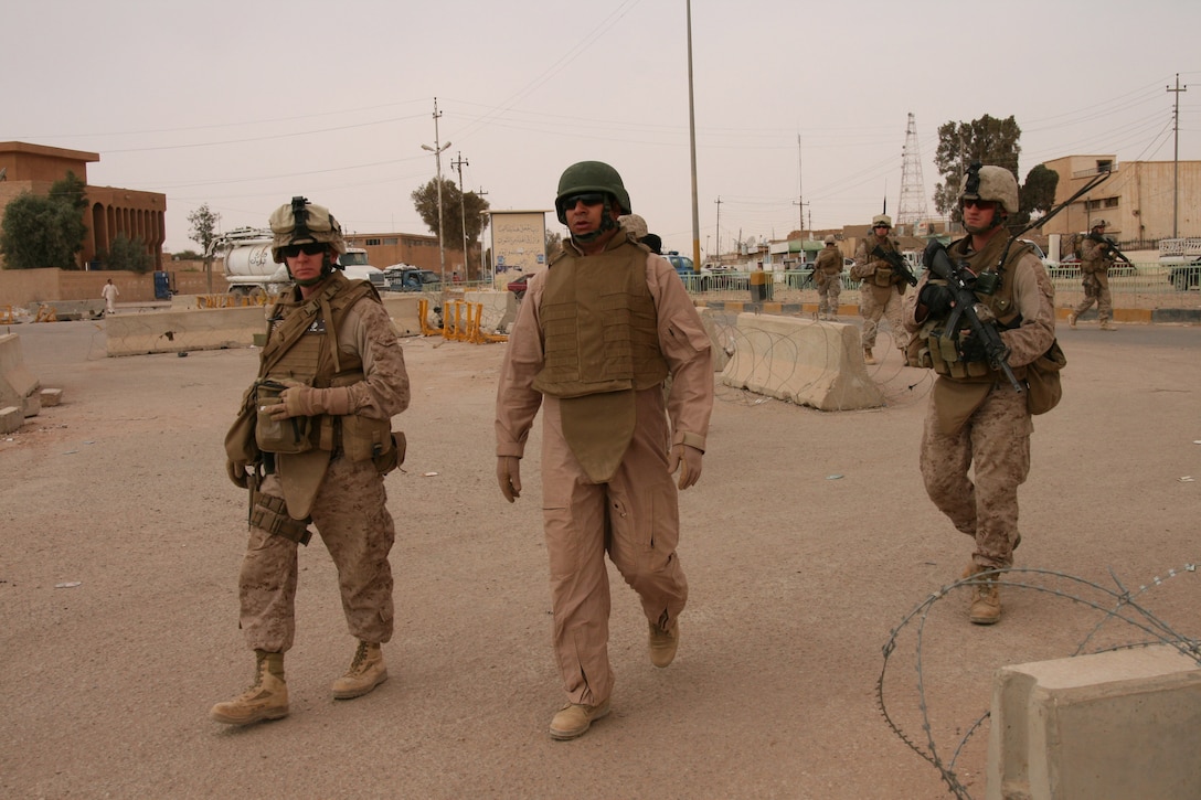 Navy Cmdr. Dennis McKenna (left), battalion surgeon for 2nd Battalion, 25th Marine Regiment, Regimental Combat Team 5, walks the streets of Rutbah, Iraq, on a security patrol Oct. 21 with Akram Shawky Mohammed (center), his Arabic interpreter and Marines and sailors from the battalion's Weapons and Golf companies.  McKenna is also the battalion's economics line of operations officer, responsible for assisting the local Iraqi leadership in establishing an economic base in the city.  He conducted "economic atmospherics" Oct. 20-21 to gain a better understanding of the overall economic situation and to work with Rutbah government officials to formulate a plan to spur economic growth.