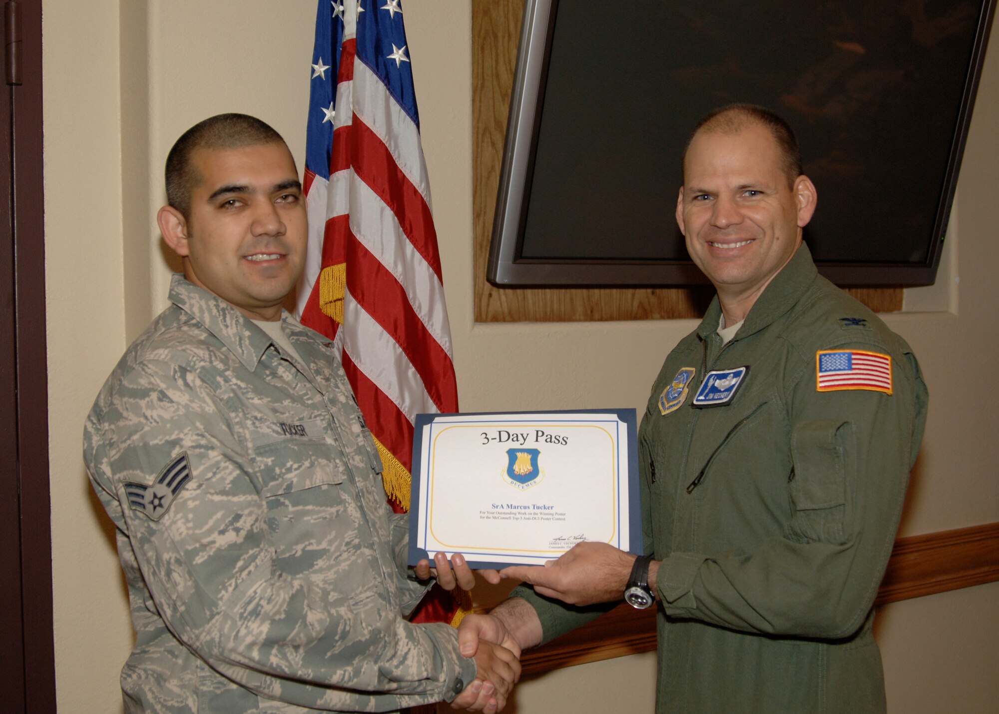 MCCONNELL AIR FORCE BASE, Kan. -- Senior Airman Marcus Tucker, 22nd Logistics Readiness Squadron, receives a three-day pass from Col. James C. Vechery, 22nd Air Refueling Wing commander, during a conference Oct. 16. Airman Tucker designed the winning anti-driving under the influence poster for a base-wide competition to help raise awareness about driving intoxicated. (Photo by Senior Airman Laura Suttles)