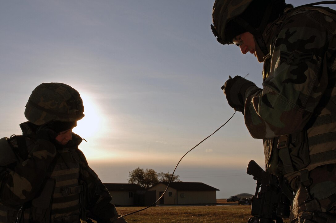 (Left to Right) Airmen 1st Class Jeana Whiteman and Steven Scalley, 28th Security Forces Squadron police officers, cut communication wire for secure telephone lines here, Oct. 22. The phone lines are set along a perimeter to facilitate conversation; they are controlled by a switchboard. (U.S. Air Force photo/Airman Corey Hook)