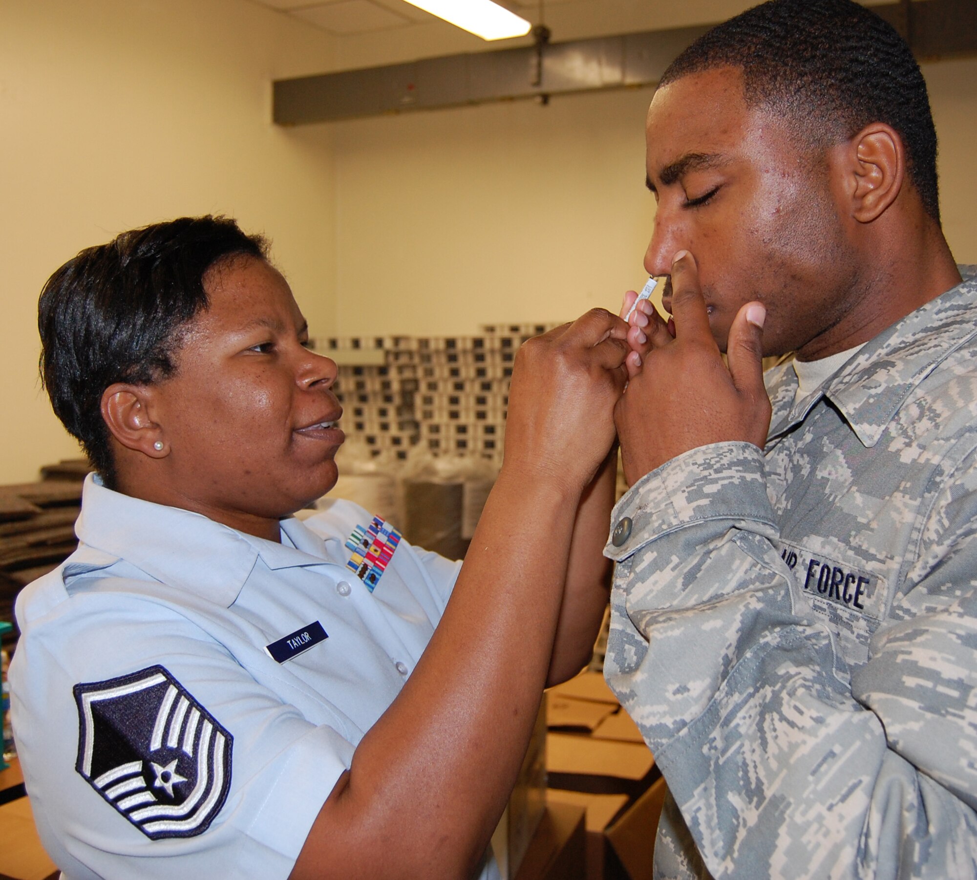 Master Sgt. Rhonda Taylor, left, 81st Medical Operations Squadron, sprays flu mist into Airman Basic Michael Brockington’s nose Monday at Bryan Hall.  Airman Brockington is a student in the 338th Training Squadron.  Members of the 81st Medical Operations Squadron were scheduled to provide flu mist and inoculations to students and faculty at several 81st Training Group buildings this week.  Keesler has received a large portion of this year’s vaccine supply and Keesler Medical Center currently is immunizing all eligible members.  Flu mist is available for patients ages 2-49 years and is mandatory for active-duty members, unless precluded by a serious medical condition.   All squadrons are being scheduled with the immunization office.  To set up a time and date, squadron representatives can call Master Sgt. Henry Owes, 376-3560. For more information about the vaccine, call the immunization office, 376-3553.  (U.A. Air Force photo by Steve Pivnick)