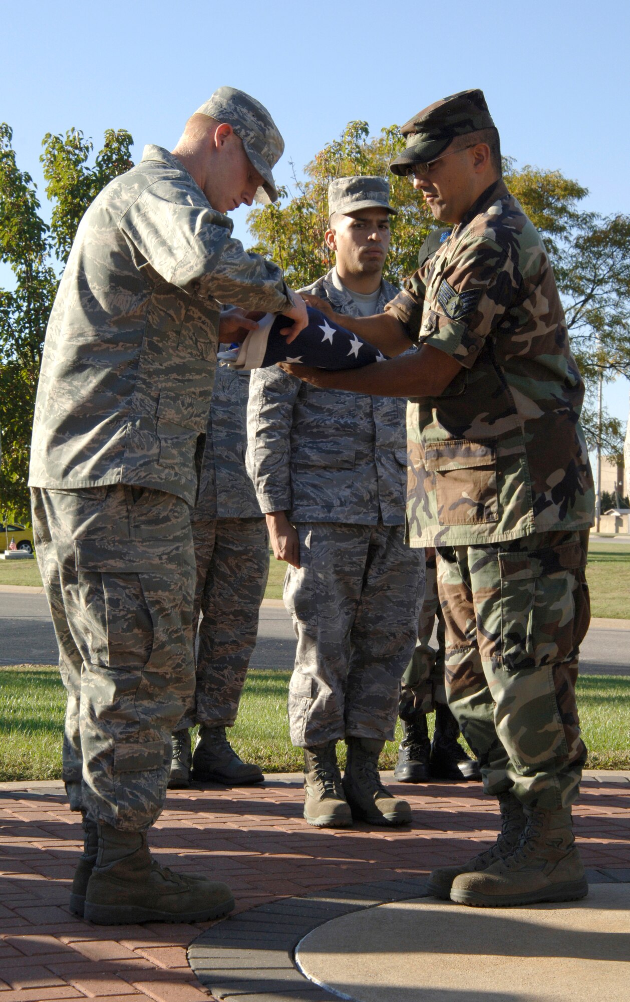 MCCONNELL AIR FORCE BASE, Kan. -- Airman 1st Class James Welker, Alvaro Cermeno and Staff Sgt. Julio Vega participate in a flag folding ceremony outside building one during the 22nd Communication Squadron retreat ceremony, Oct. 16. (Photo by Senior Airman Laura Suttles)