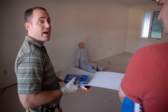 Special Agent Jeremy Meng talks to Special Agent Matthew Tonay prior to starting his sketch of the exercise crime scene in base housing Oct. 17. The local Office of Special Investigations detachment held the exercise simulating a suicide to test their crime scene investigation skills and work with their counterparts in the 437th Security Forces Squadron and the 437th Airlift Wing Law Center. Agents Meng and Tonay are assigned to AFOSI Det. 310. (U.S. Air Force photo/Staff Sgt. Sam Hymas)