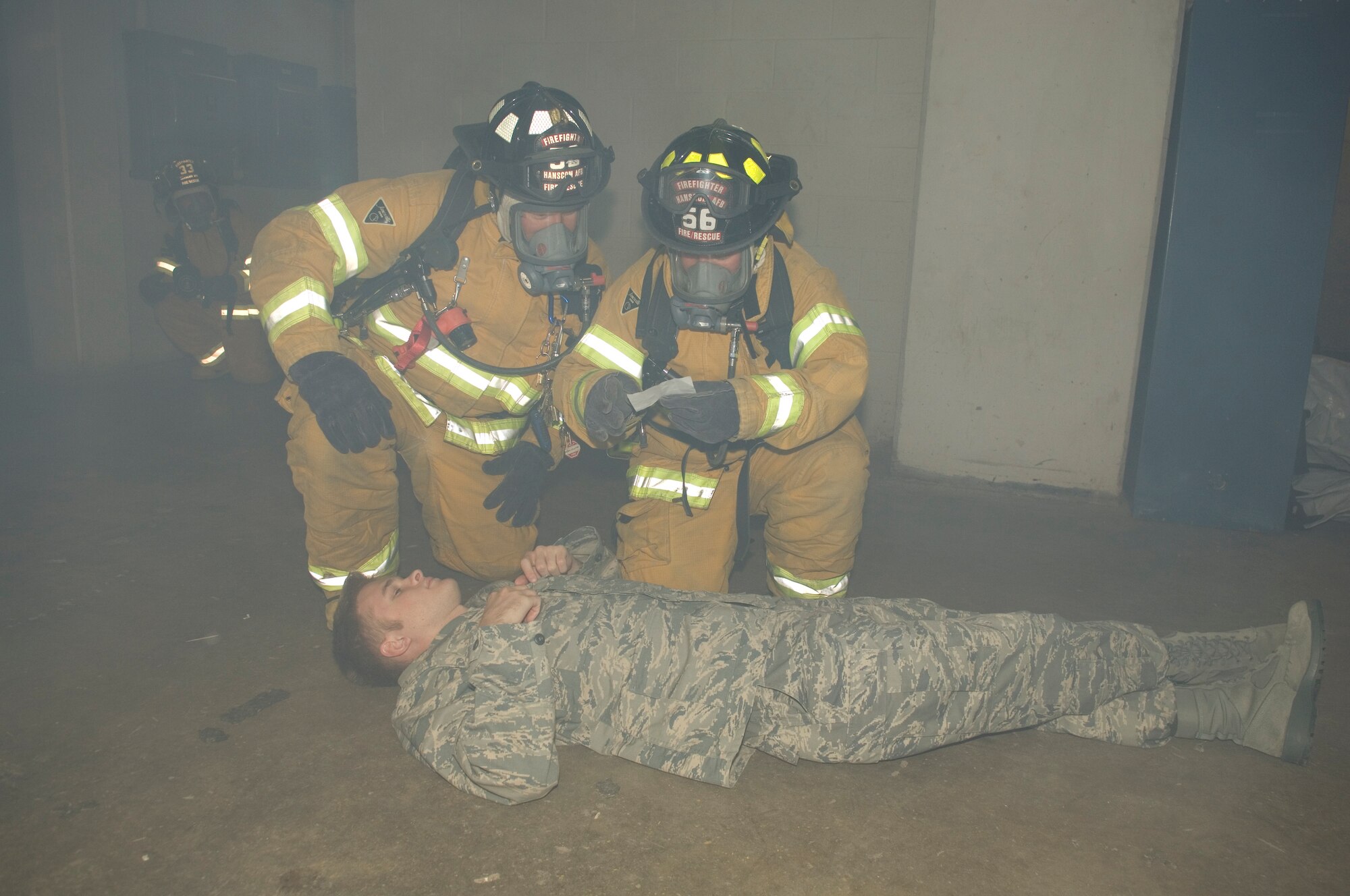 HANSCOM AIR FORCE BASE, Mass. – Firemen triage a simulated victim in the smoke filled basement of building 1102F, during an emergency management exercise scenario on Oct. 20. Pictured are Firemen Tim Shea (left) and Keith Williams (right). In addition to the emergency operations exercise, more than 230 personnel took part in readiness training at Camp Patriot in preparation for the start of next week’s Unit Compliance and Targeted Readiness Inspections.  (U.S. Air Force photo by Rick Berry)