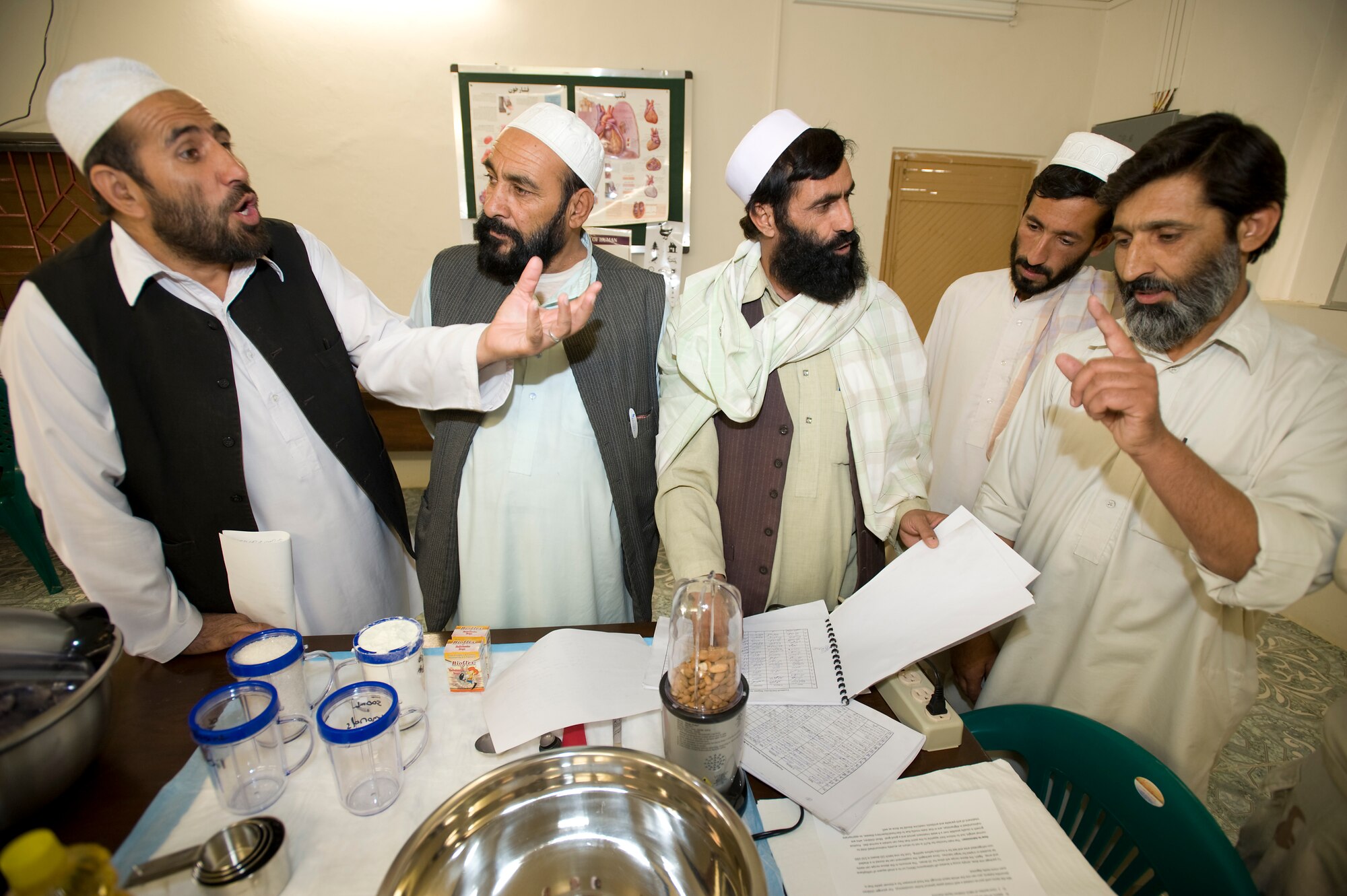 (Right) Dr. Zamarai Sultan discusses results he has seen using "strong food" over the course of two months to treat malnourished children from the Shajoy public health administration office. "Strong food" is a vitamin enriched high calories food supplement used to combat malnutrition. The Shajoy public health administration staff has been using the low-cost and locally produced food supplement to treat more than 400 malnourished children in two months. The doctor said he has seen most patients gain 1 to 1.5 kilograms a week while taking “strong food.” (U.S. Air Force photo/Master Sgt. Keith Brown)
