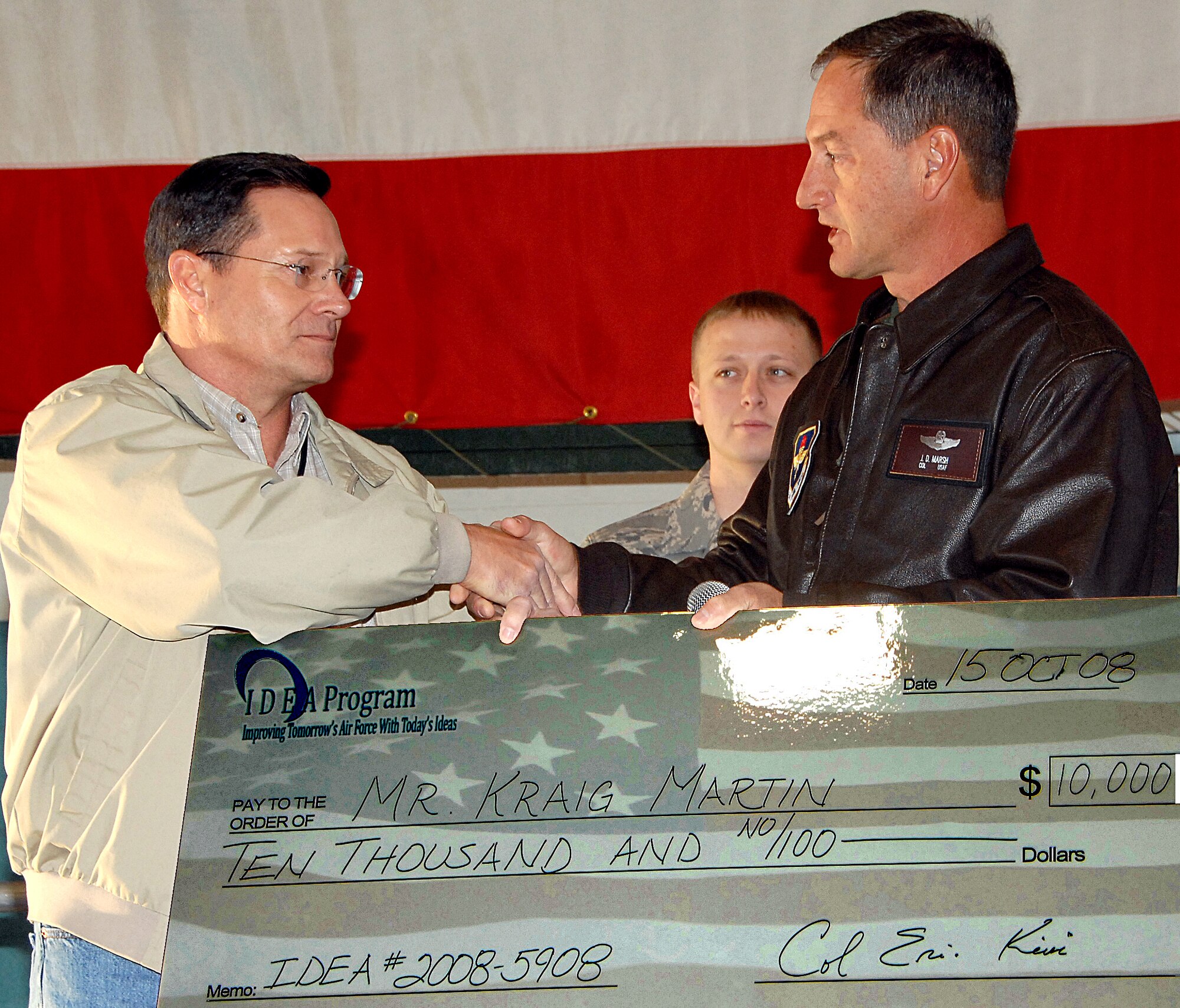 Kraig Martin, 58th Maintenance Group, accepts a check for $10,000 from Col. James D. Marsh, 58th Special Operations Wing vice commander, for his money-saving idea. He submitted his plan through the Air Force Smart Operations for the 21st Century Idea Program. He suggested using different vibration measuring equipment in a new test harness for the T-56 engine. His method saves the Air Force about $1,500 for each of the 2,095 engines. ?Hannah Chang, 377th Air Base Wing (Idea Program) point of contact, and Staff Sgt. Jason Macanay, 58th MXG point of contact, were both very helpful,? Mr. Martin said. He said he?s already working on other ideas he plans to submit. U.S. Air Force photo by Todd Berenger