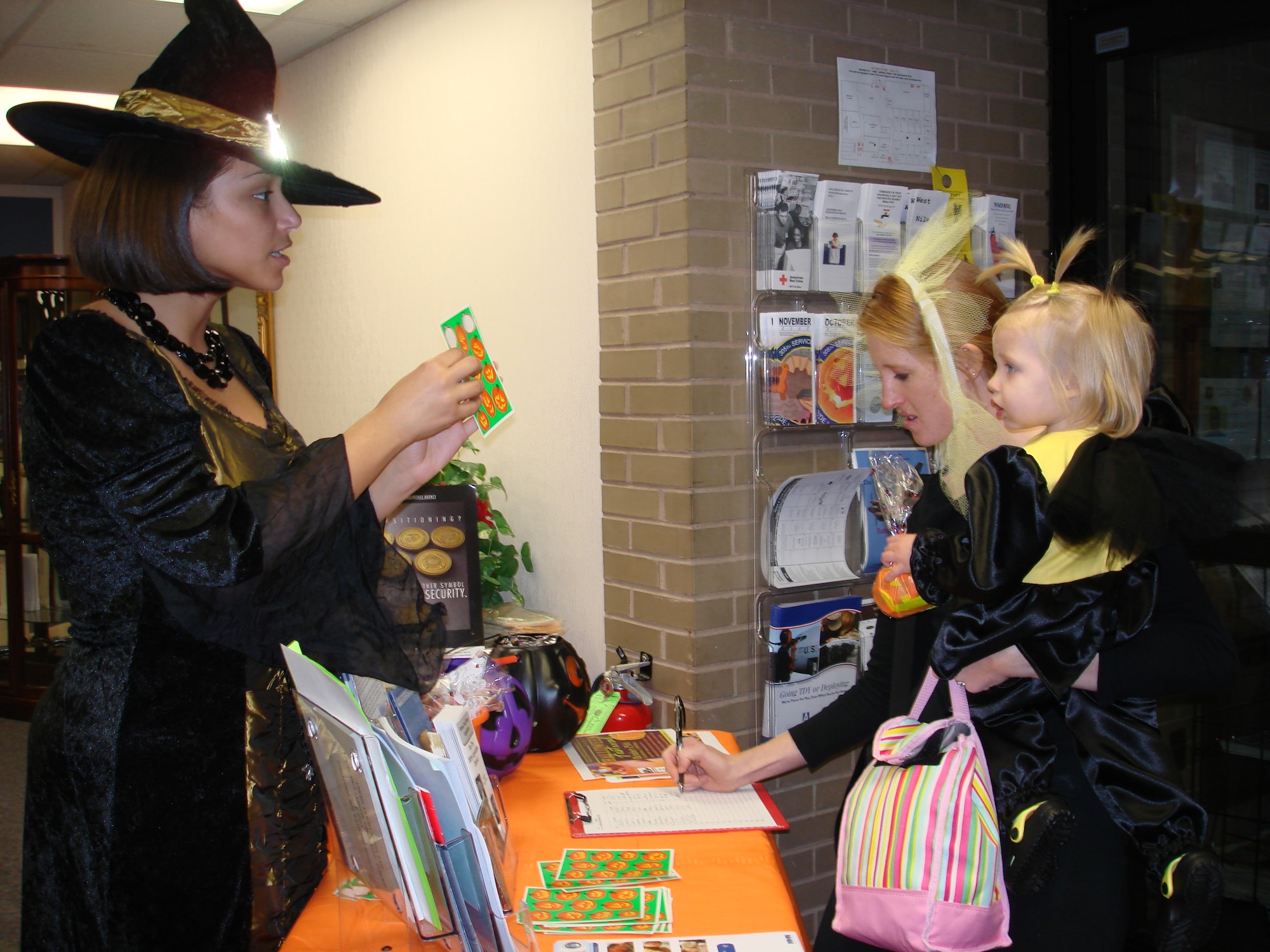 Left, A Hearts Apart volunteer welcomes families to the annual pre Halloween-alternate theme party at the Airman and Family Readiness Center Oct. 17. Children enjoyed food, games and crafts and showed off their Halloween costumes. The event is one of the A&FRC monthly treats for military family members of deployed or remotely- assigned Airmen. (U.S. Air Force photo/Staff Sgt. Francis Lalic) 