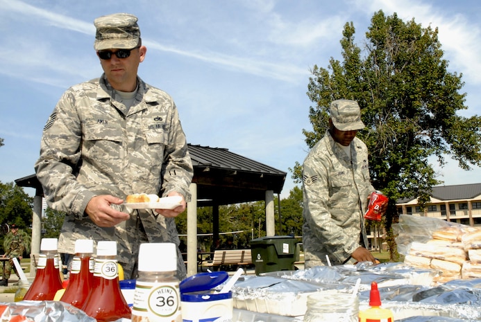 Tech. Sgt. Ivan Aiken, left, and Senior Airman DeMarcus Johns help themselves to hamburgers, hotdogs and bratwurst during the Oktoberfest held on base Oct. 17. The Charleston AFB Top 3 provided food, drinks and entertainment for junior?enlisted Airmen during the annual event.  Sergeant Aiken is with the 373rd Training Squadron, Detachment 5 and Airman Johns is with the 437th Maintenance Squadron. (U.S. Air Force photo/Staff Sgt. Jennifer Arredondo)