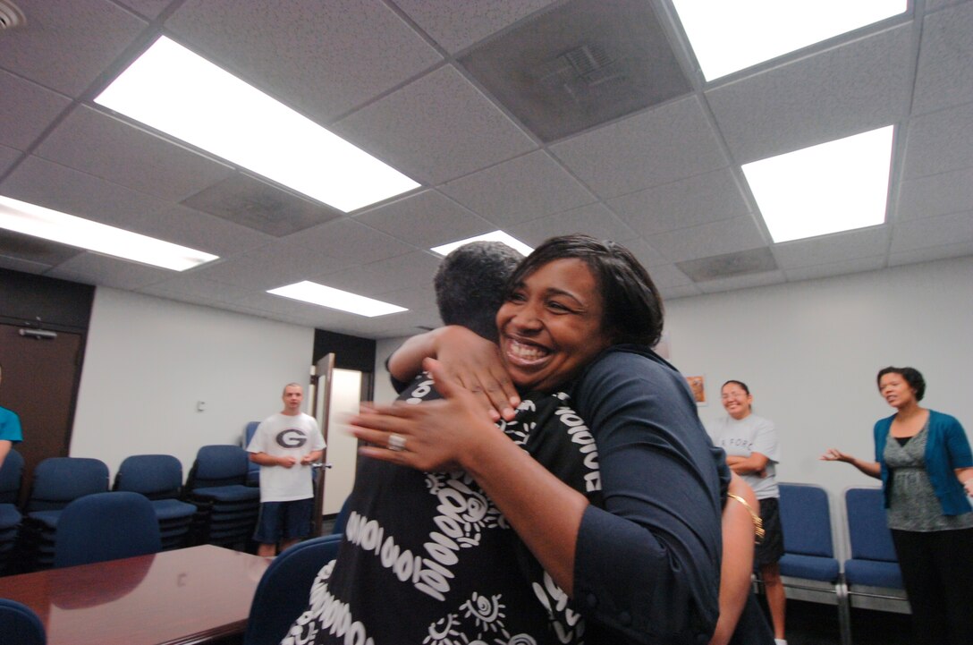 “Chunky Monkey” team member Sharnte Crown, right, gives teammate Lisa Morton a congratulatory hug after final weigh-in. Approximately 40 combined military and civilian members, comprised of eight teams from the 316th Force Support Squadron, stood in line for their final weigh-in Oct. 15. (U.S. Air Force photo by Bobby Jones)