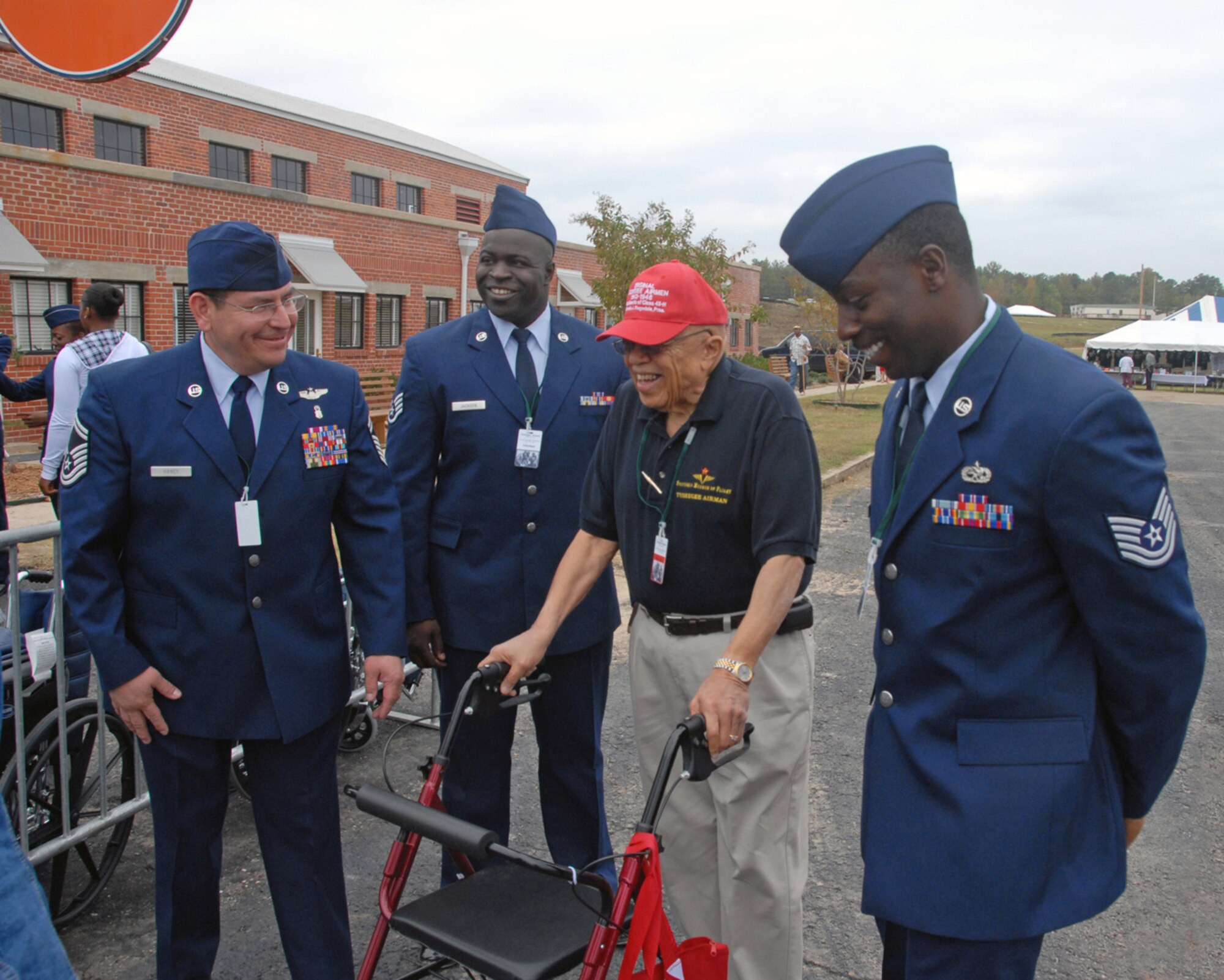 From left, 908th Airlift Wing members Senior Master Sgt. Tom Haney, Staff Sgt. Charles Jackson and Tech. Sgt. D'Wayne Guice lend assistance to an original Tuskegee Airman preparing to gain entrance to the grand opening activities for the dedication of the Tuskegee Airmen National Historic Site at Moton Field in Tuskegee, Ala. Oct. 10. Sergeants Haney, Jackson, Guice, and 23 other 908th AW from nearby Maxwell AFB serving as escorts provided assistance to 300 or so surviving Tuskegee Airmen who attended the ceremony. The famed black aviators Airmen overcame segregation and prejudice to become one of the most highly respected fighter groups of World War II. Their achievements, together with the men and women who supported them, paved the way for full integration of the U.S. military (U.S. Air Force Photo by Lt. Col. Jerry Lobb)         
