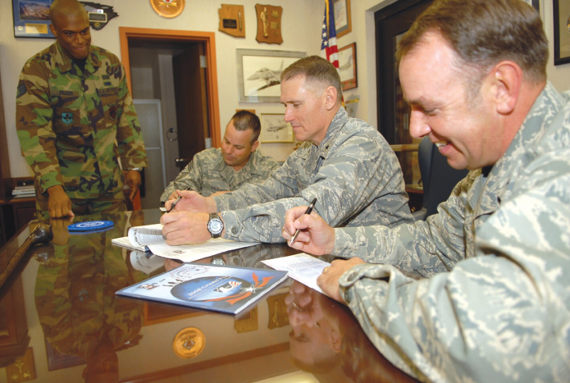 Brig. Gen. Kurt Neubauer 56th Fighter Wing commander, center, reviews the Combined Federal Campaign charity booklet preparing to make a donation, as Col. Hank Reed, 56th FW vice commander, right, and Chief Master Sgt. Randall Raper, 56th FW command chief, fill out their forms. Staff Sgt. Andrew Fraser, 56th FW emergency actions controller and CFC representative provides guidance. (U.S. Air Force Photo/Senior Airman Tong Duong.)