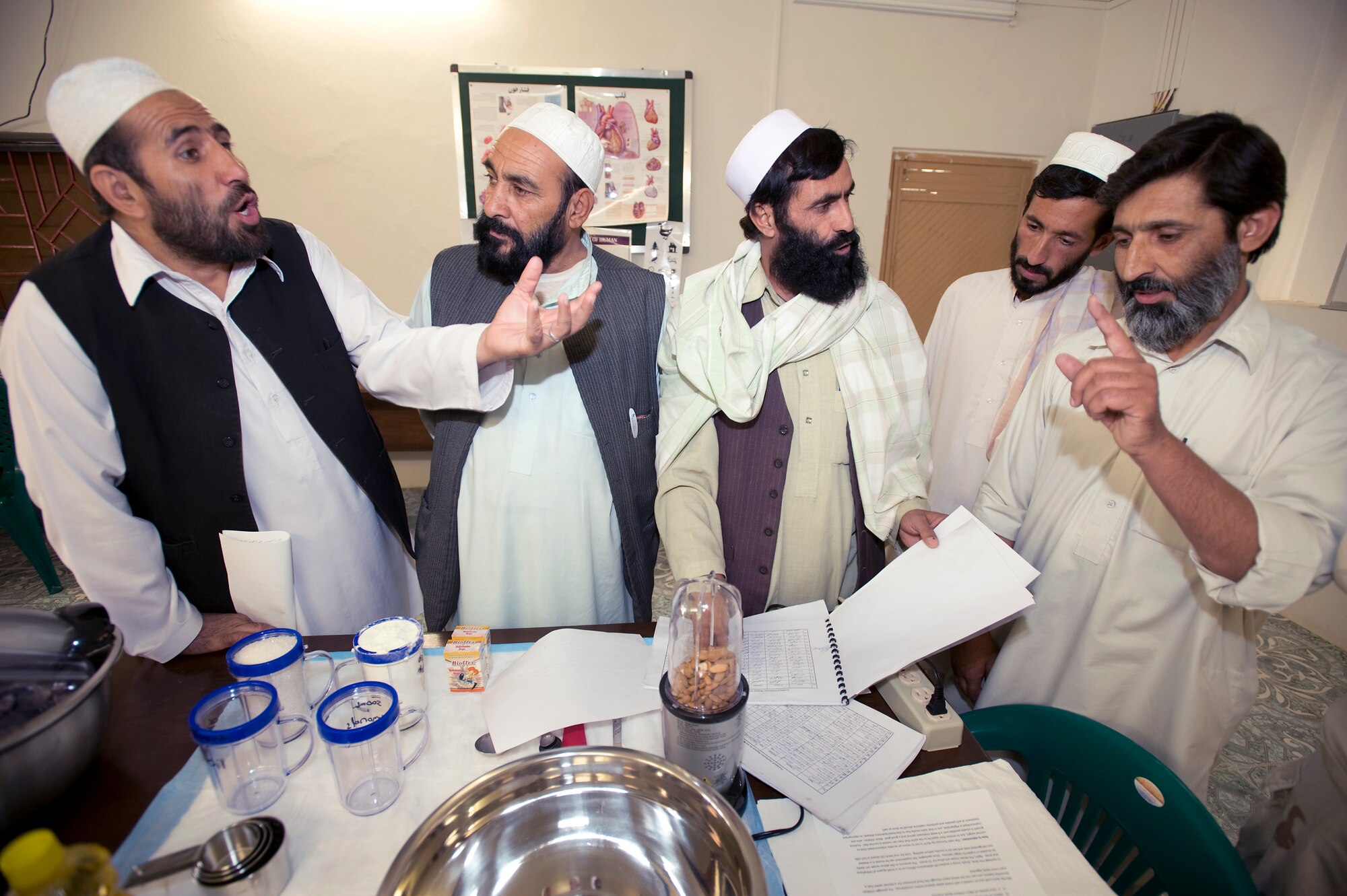 Dr. Zamarai Sultan (right) discusses results he has seen using "strong food" over the course of two months to treat malnourished children from the Shajoy public health administration office Oct. 15 in Qalat, Afghanistan. "Strong food" is a vitamin enriched high calorie food supplement used to combat malnutrition. The Shajoy public health administration staff has been using the low-cost and locally produced food supplement to treat more than 400 malnourished children in two months. The doctor said he has seen most patients gain 1 to 1.5 kilograms a week while taking "strong food." (U.S. Air Force photo/Master Sgt. Keith Brown) 
