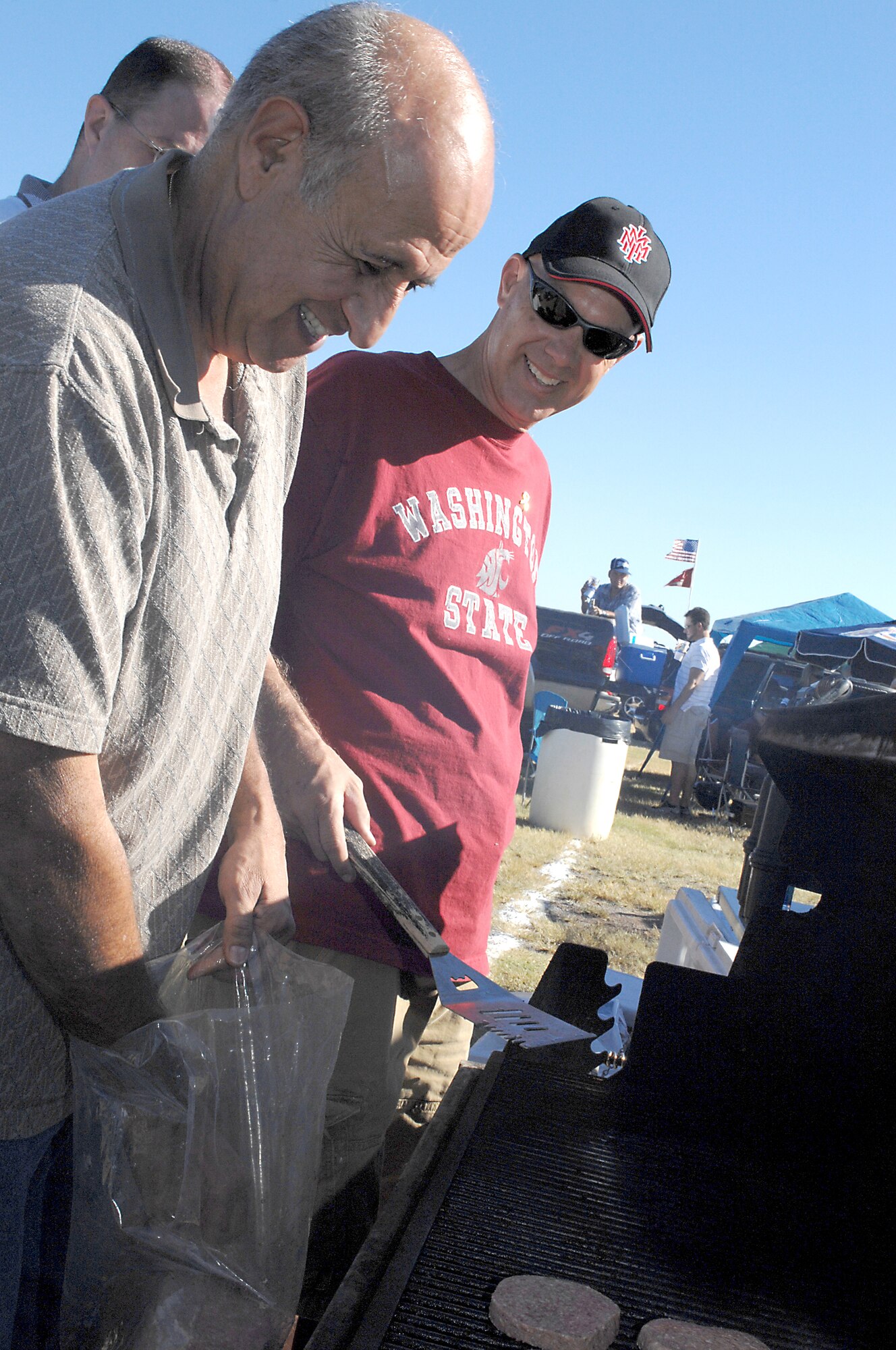 Juan Mejia, 49th Operations Group secretary, and Senior Master Sgt. Scott Thomsen, 49 OG, put burgers on the grill during the tailgate party before the New Mexico State University game against San Jose State at NMSU, October 18. The 49 OG from Holloman Air Force Base, N.M., hosted the party for Team Holloman Airmen, family and friends. (U.S. Air Force photo/Airman Sondra M. Escutia)