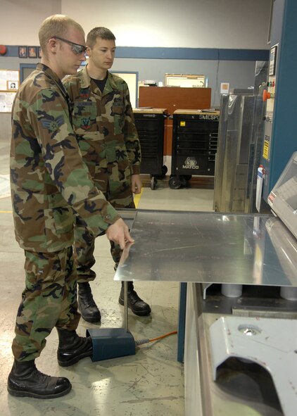 Senior Airman Brock Roehm, 4 Equipment Maintenance Squadron, slides a piece of aluminum into the Power Shear Cutter in the Sheet Metal shop on Seymour Johnson Air Force Base, N.C., Oct. 21, 2008. Sheet Metal Airmen attend a four month technical school in Pensacola, FL to learn everything from general shop practices to aircraft sanding, prime and paint. (U.S. Air Force photo by Airman 1st Class Makenzie Lang)