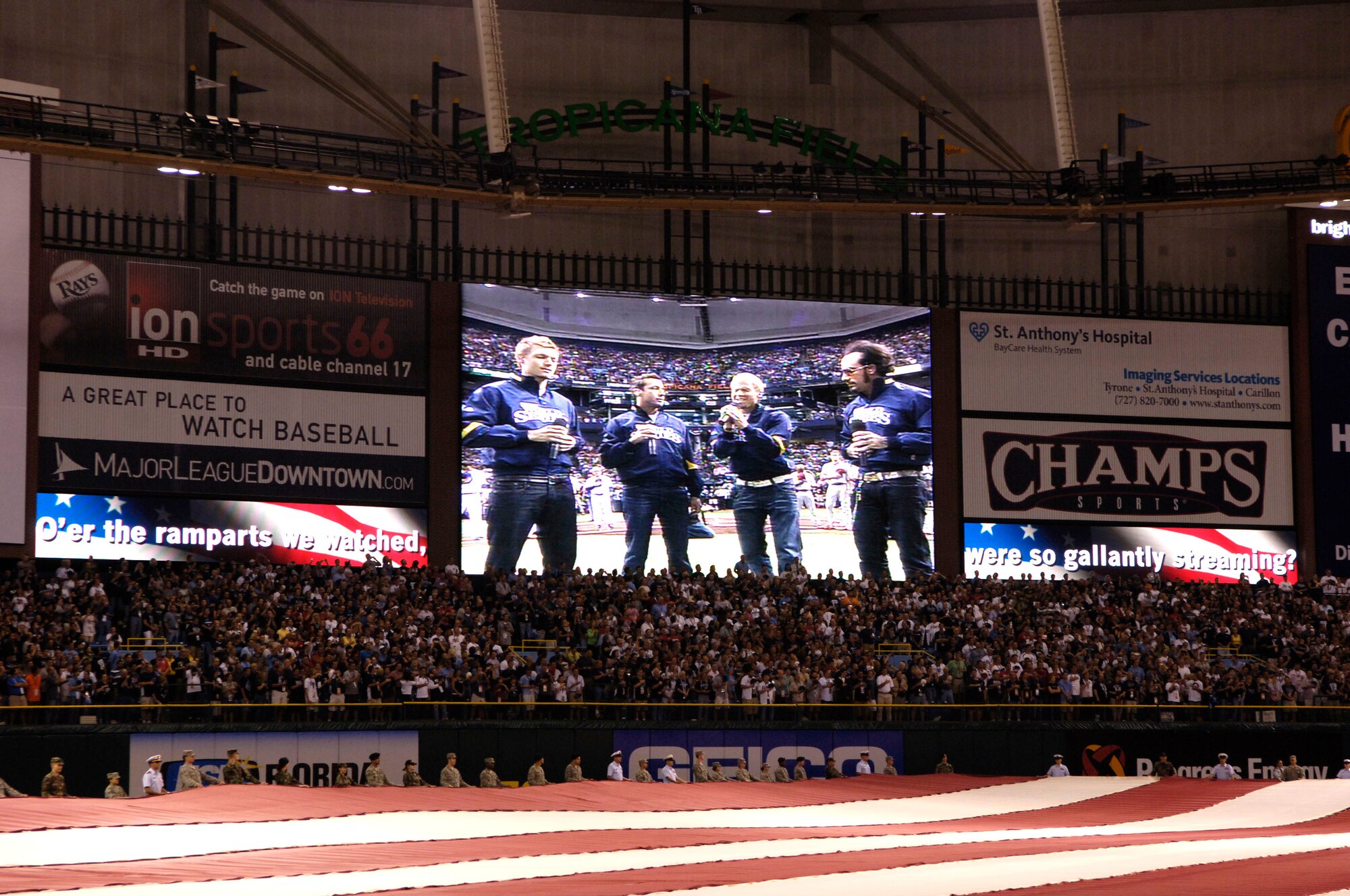 Members of the 6th Air Mobility Wing along with members of the U.S. Coast Guard assigned to sector St. Petersburg, Fla., hold the American Flag during the National Anthem sung by the Backstreet Boys during the first game of the World Series Oct. 22, where the Philadelphia Phillies took on the Tampa Bay Rays. (U.S. Air Force Photo by Senior Airman Stephenie Wade)