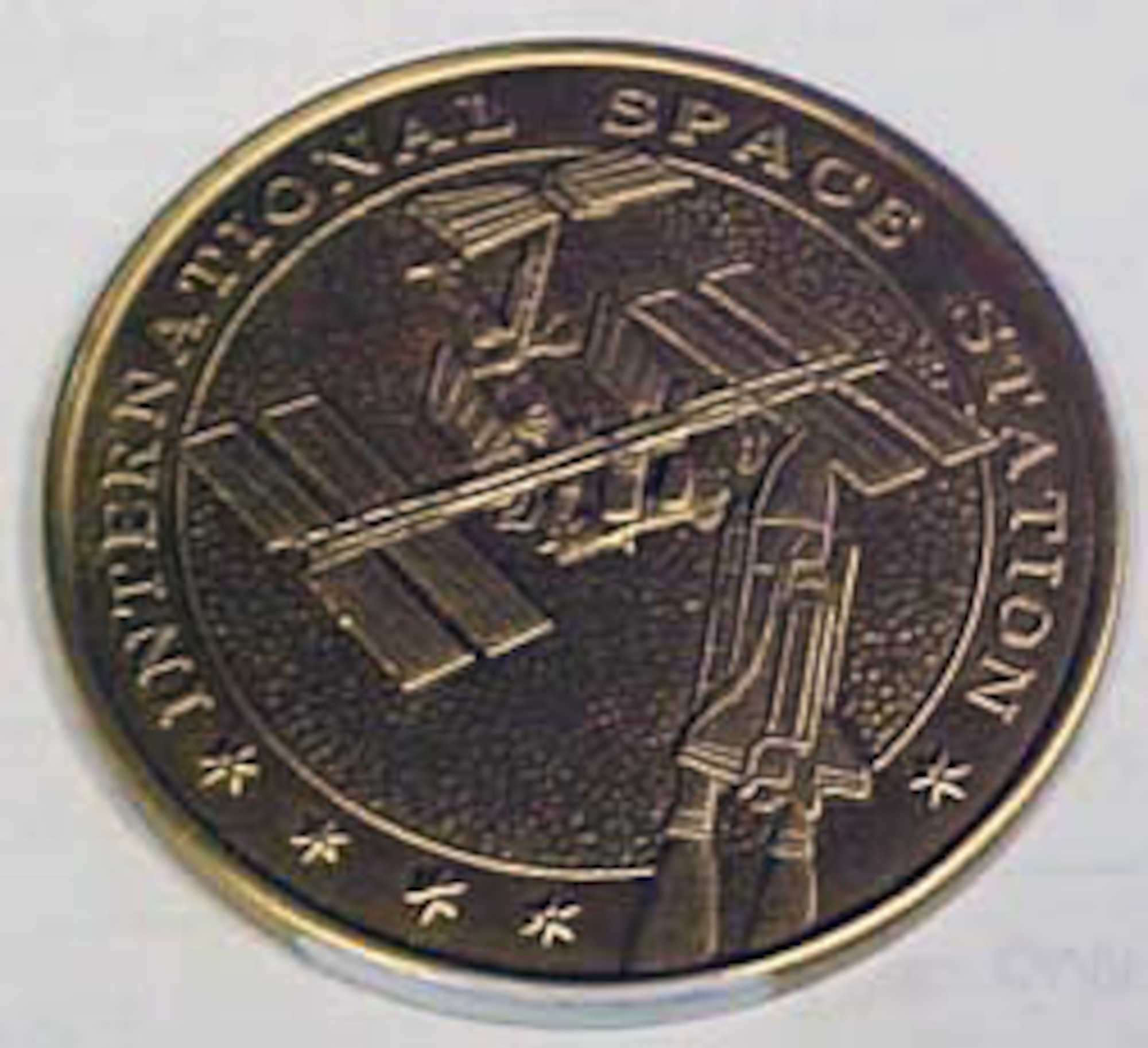 This gold commemorative coin shows the International Space Station and space shuttle. It contains metal from the unity node flown on Mission STS-88. (U.S. Air Force photo)