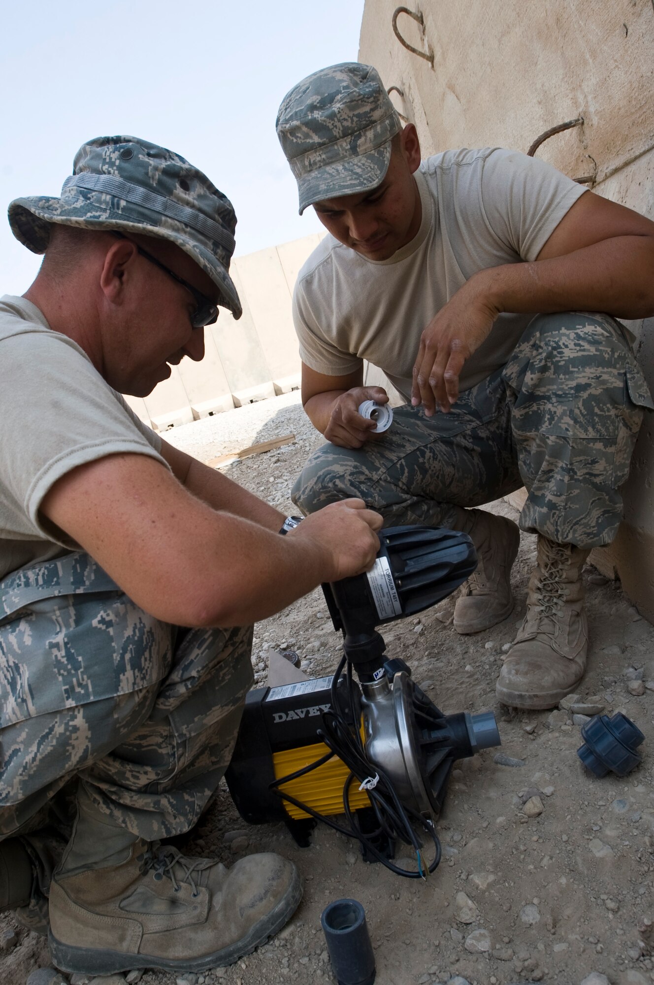 ALI BASE, Iraq -- Staff Sgts. Dustin Bray and Steven Javinar, 407th Expeditionary Civil Engineer Squadron, prepare to attach a water pump to the water tank Oct. 22, 2008. The water tank will provide running water for a snack bar. People stationed here now have another Army and Air Force Exchange Service store to purchase necessities. Bray and Javinar are deployed from F.E. Warren Air Force Base, Wyo. (U.S. Air Force photo/Senior Airman Christopher Griffin) 
