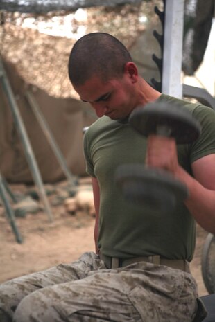 Seaman Nicolaos Vassiliades, corpsman for Provisional Rifle Platoon 3, Regimental Combat Team 5, does a set of seated dumbbell curls at the Traffic Control Point 3 gym in Rawah, Iraq, Oct. 25. Vassiliades and the Marines of PRP-3 use their free time to stay fit and combat ready.::r::::n::