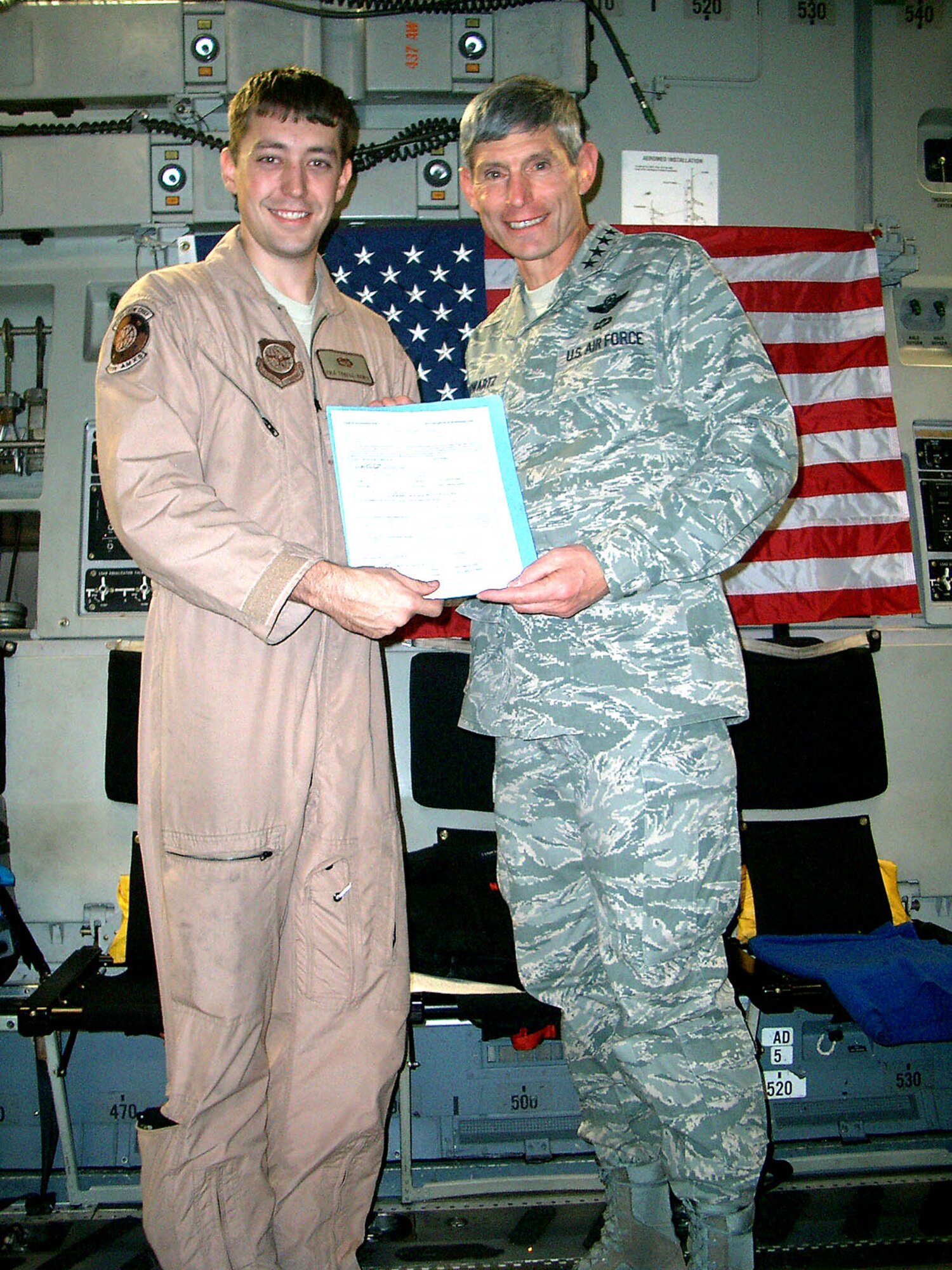 Air Force Chief of Staff Gen. Norton A. Schwartz presents Senior Airman Tyrell Haney his reenlistment documentation after reenlisting him Oct. 23 in a ceremony aboard a C-17 Globemaster III cruising above the U.S. Central Command area of operations. Airman Haney, a 437th Aircraft Maintenance Squadron crew chief from Charleston Air Force Base, S.C., already has deployed twice to CENTCOM within his first 3 ? years of enlistment. (U.S. Air Force photo/Senior Master Sgt. Sean E. Cobb) 