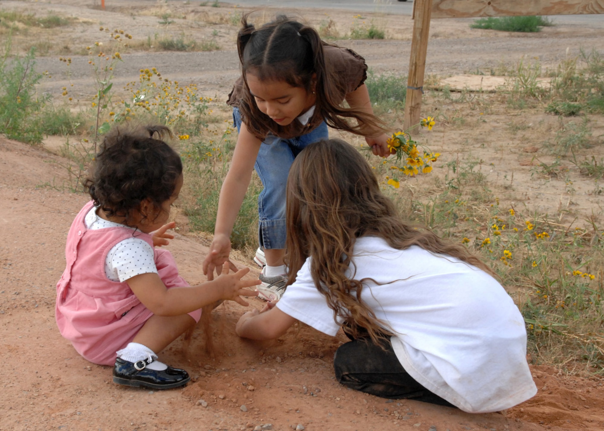 Audryanna Duran and Natalie Iglesias, daughters of Lizabeth Duran, plant yellow flowers with TracyAnn Edwards in Alamorgordo, N.M., October 12. The Duran family came out for the groundbreaking ceremony supported by Habitat for Humanity for the building of their new home. (U.S. Air Force photo/Airman 1st Class Veronica Salgado)