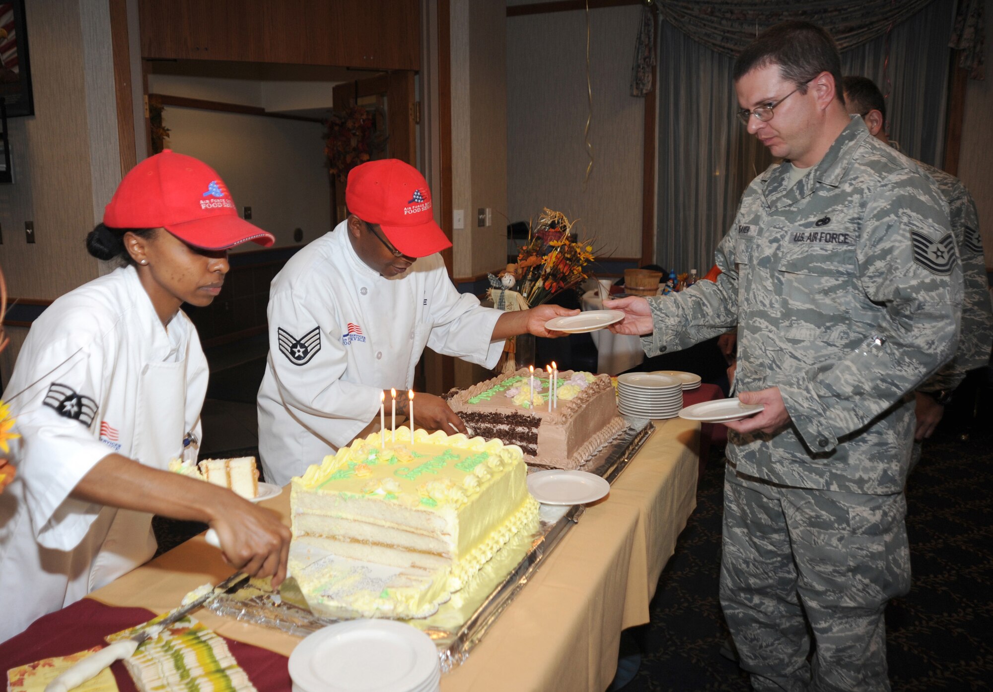 CANNON AIR FORCE BASE N.M.-- Senior Airman Yemisirach Alemayehu and Staff Sgt. Ronald Tifre, 27th Special Operations Services Squadron, serve birthday cake to Tech. Sgt. Benjamin Weaver, 27th Special Operations Equipment Maintenance Squadron, at the Quarterly Birthday Meal Oct. 23 held at the Pecos Trail Dining Facility. To go along with tradition, the oldest and youngest Airmen attending the meal cut the first piece of cake. (U.S. Air Force photo by Airman Maynelinne De La Cruz)