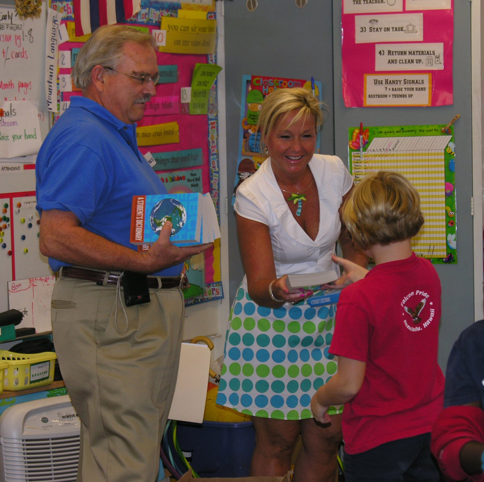 From left, Ernie Anderson, President select, Rotary Club of Pearl Harbor and Kathy Wolford, wife of Vice Commander of the 15th Airlift Wing in distributing the dictionaries to students at Hickam Elementary School on Oct 23.  (U.S. Air Force photo by Jeff Nicolay)