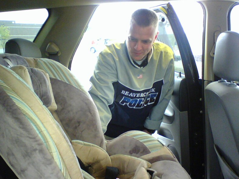 Beavercreek Police officer Adam Kempf inspects a vehicle to ensure proper child safety seat installation at Wright-Patterson Air Force Base Oct. 24.  More than 70 base families signed up for the free checks to ensure their children were safely buckled in.  Technicians identified installation errors in more than 80 percent of vehicles, including instances of recalled or defective child safety seats in nearly one out of every four vehicles inspected.  Recalled seats were replaced free of charge by event sponsor, Chrysler.  Inspectors said the results are not uncommon and encourage others to visit seatcheck.org for more information.  Kempf underwent 32 hours of training to receive child safety seat technician certification. (U.S. Air Force photo/Derek Kaufman)