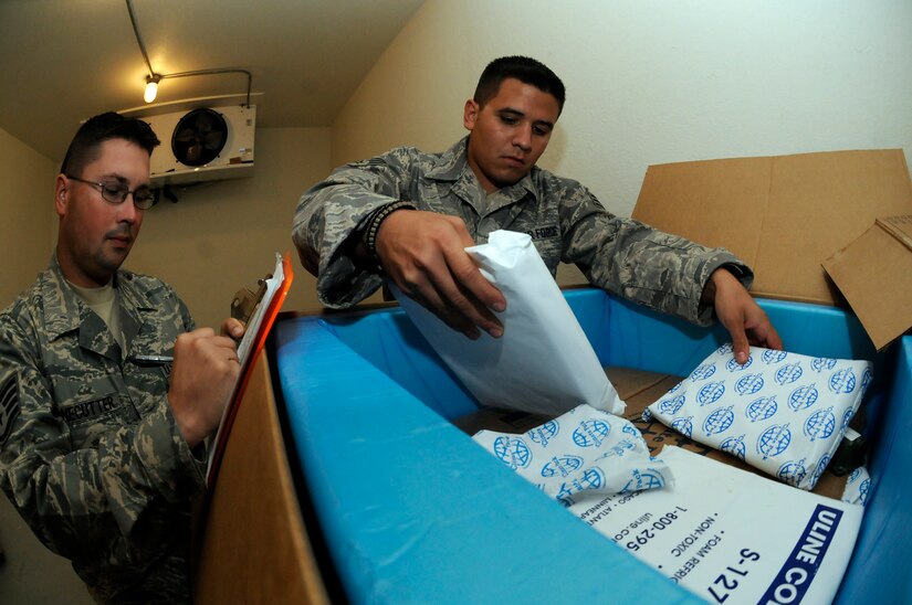 Senior Airman Michael Rodriguez stacks cold bricks on top of medical supplies as Staff Sgt. Michael Bonecutter logs the reicing time Oct. 23 at an air base in Southwest Asia. The unit processes thousands of pounds of medical supplies and equipment for shipment to units in the area of responsibility. Airman Rodriguez, an 8th Expeditionary Air Mobility Squadron special handling technician, is a native of Saint John, Mich. He is deployed from Charleston Air Force Base, S.C. Sergeant Bonecutter, an 8th EAMS special handling supervisor, is a native of Pilot Grove, Mo. He is deployed from Little Rock AFB, Ark. (U.S. Air Force photo/Staff Sgt. Darnell T. Cannady) 
