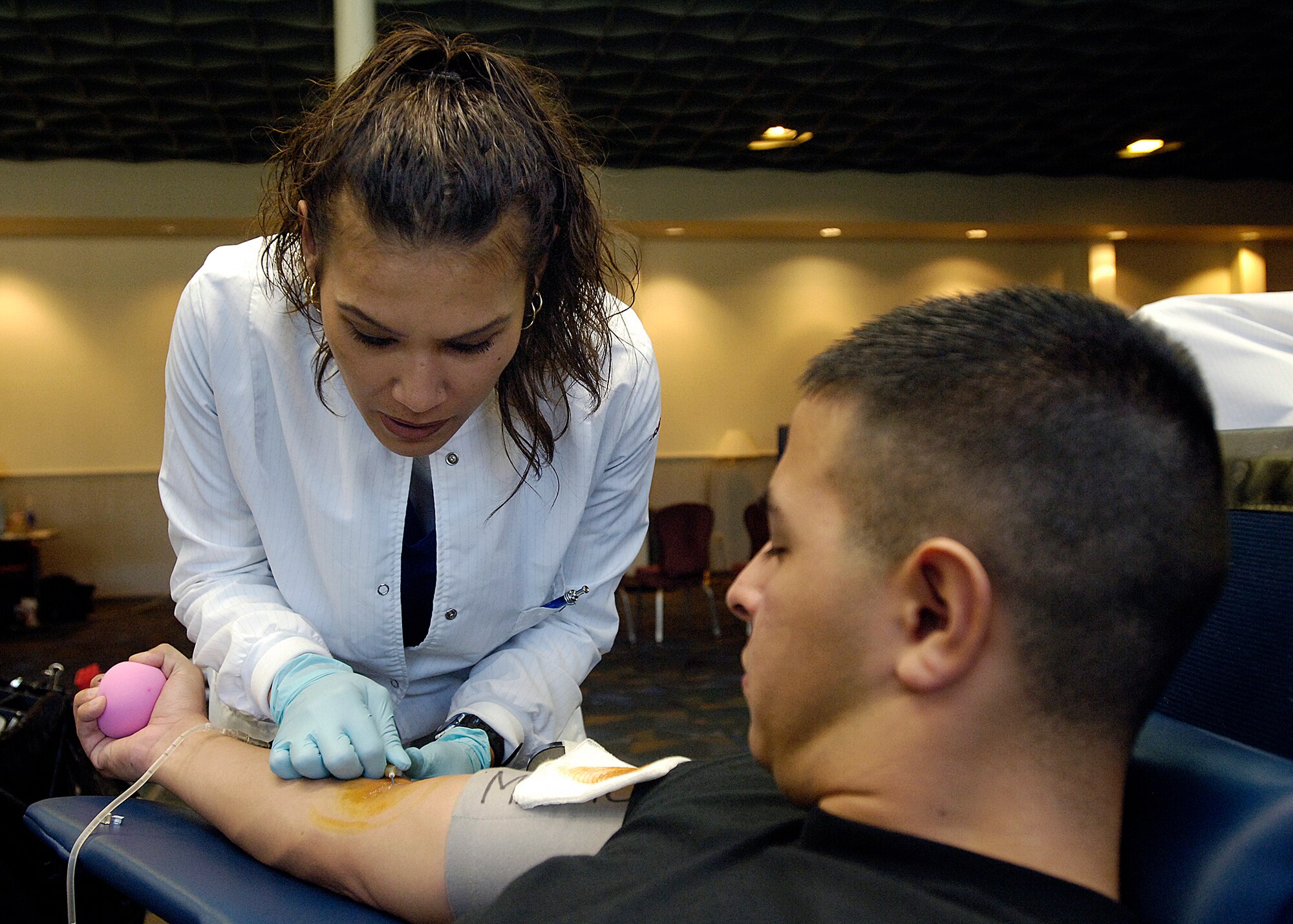 FAIRCHILD AIR FORCE BASE, Wash. – U.S.  Army phlebotomist Reiko Adsuara prepares to draw blood while Airman 1st Class Steve Gamboa, 93rd Air Refueling Squadron boom operator, lies back in his chair anxiously awaiting a needle prick Oct. 23. The Airman’s donation will help support troops in forward-deployed locations. (U.S. Air Force photo / Senior Airman Eunique Stevens )
