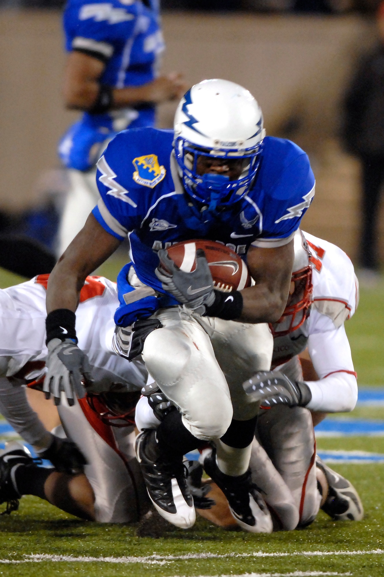 U.S. Air Force Academy freshman tailback Asher Clark works his way through tacklers for a short gain up the middle. Clark was the Falcons leading rusher, carrying the ball 23 times for 86 yards during the 23-10 win over New Mexico, Oct. 23 at Falcon Stadium in Colorado. With the win, the Falcons are now bowl-eligible at 6-2 and return to the gridiron Nov. 1 at Army. (U.S. Air Force photo/Mike Kaplan)