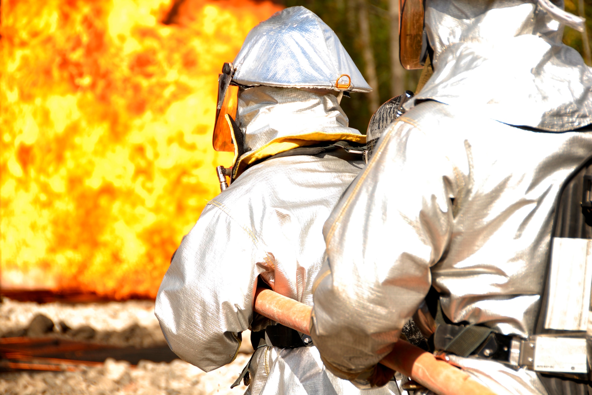 Two handline team members of the 127th Fire Department at Selfridge ANGB,  Mich., walk into a blazing inferno while pointing a charged fire hose during a simulated aircraft crash site drill Oct. 18, 2008 at the CRTC in Alpena, Mich. The handline team trains at fast response and accurately raining water onto a fire, extinguishing it promptly.  (U.S. Air Force photo by Technical Sgt. David S. Kujawa)