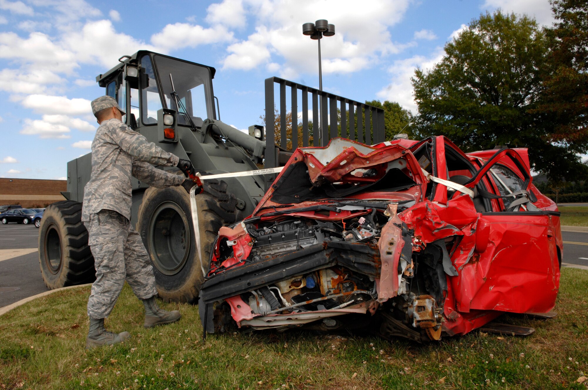 Senior Airman Brian Hitlt, 11th Logistics Readiness Squadron, unties a wrecked car Oct. 23 in Bolling's base exchange and commissary parking lot. The car is a visual aid used by the 11th Wing Safety Office to remind people to practice vehicle safety as part of the Fall Safety Campaign. (U.S. Air Force photo by Airman Tim Chacon)