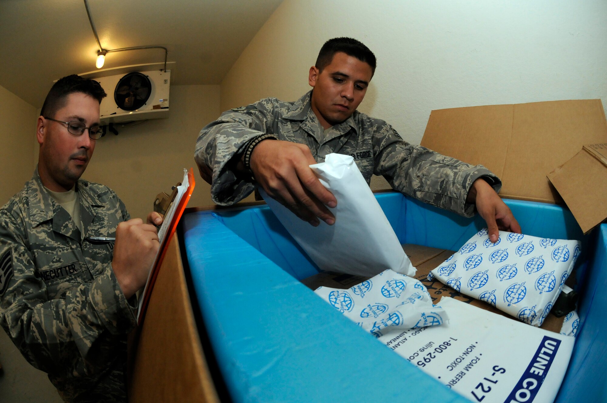 Senior Airman Michael Rodriguez, 8th Expeditionary Air Mobility Squadron special handling technician, stacks cold bricks on top of medical supplies, while Staff Sgt. Michael Bonecutter, 8 EAMS special handling supervisor, logs the re-icing time Oct. 23, 2008, at an undisclosed location in Southwest Asia. The unit processes thousands of  pounds of medical supplies and equipment for shipment to units in the AOR. One such package recently helped save a young Iraqi woman from a venomous snakebite. Airman Rodriguez, a native of Saint John, Mich., is deployed from Charleston Air Force Base, S.C., and Sergeant Bonecutter, a native of Pilot Grove, Mo., is deployed from Little Rock AFB, Ark. (U.S. Air Force photo by Staff Sgt. Darnell T. Cannady)