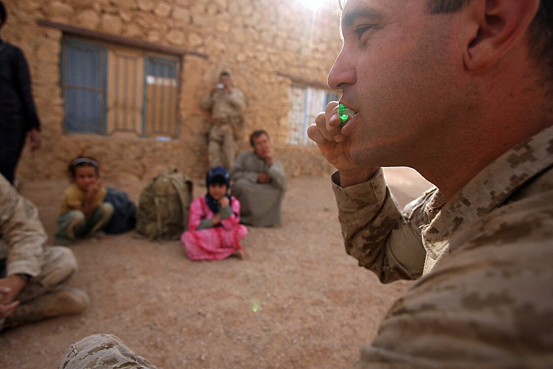 Capt. Will D. Whaley, operations officer, Border Transition Team 4222, shows Iraqi children the standard operating procedure for brushing teeth Oct. 24. Their mission is to train, mentor and advise, but Whaley, 32, Phoenix, Az., and the Marines of BTT 4222 don’t forget to provide help to western Anbar’s civilian population. The transition team headed up a small civil affairs engagement to provide local Iraqis with medical, dental and logistical aid. Though it’s not part of their primary mission, team members here have learned that reaching out to the Iraqi people will make the people more likely to reach out to Marines. Intelligence gathering and improved security is just a byproduct of good relations. The real purpose here was to see some smiles. Marines handed out toothbrushes, toothpaste and teddy bears to each patient finished with the check up. The corpsman spoke to parents about how to treat with the medicine Marines supplied to them. Kids also received a class on proper tooth brushing techniques.