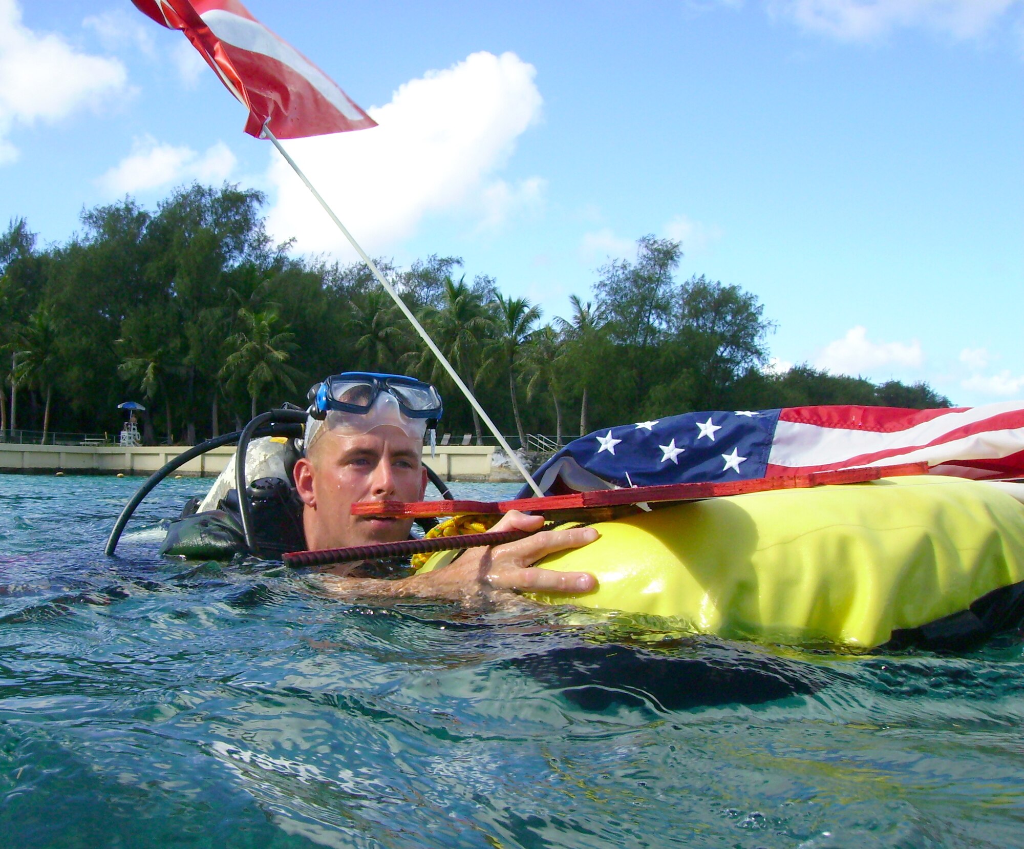 ANDERSEN AIR FORCE BASE, Guam - Staff Sgt. Stephen Johnson, 554th RED HORSE Squadron structural engineer, pushes a scuba dive flag and an American flag in preparation for his underwater reenlistment ceremony at COMNAVMAR's Gab Gab beach.  (Photo courtesy of 554th RHS)