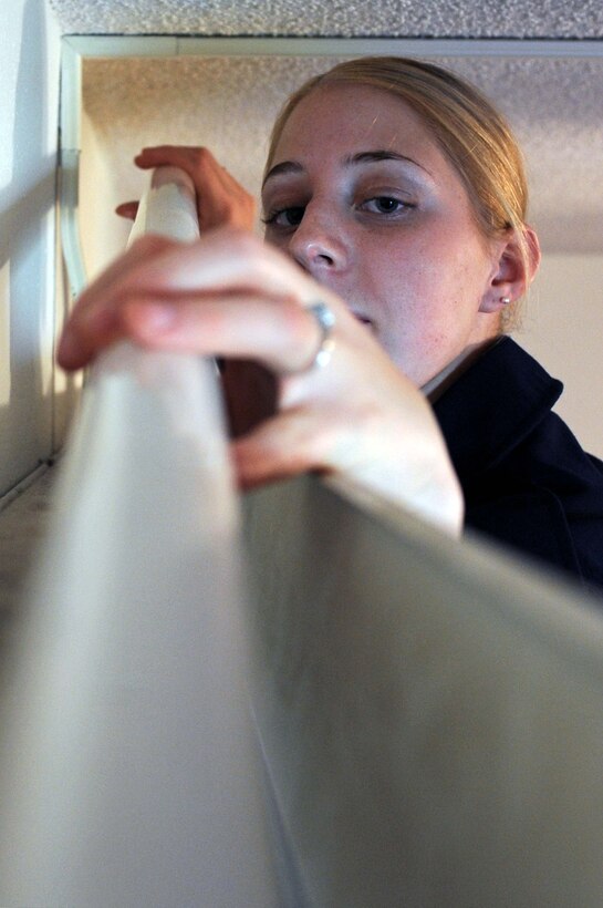 Airman Rachael Liberty, 28th Operations Support Squadron aviation resource management apprentice, installs a fluorescent light in a Washington Inn dormitory room on Oct. 27. Fluorescent lights are an energy efficient alternative to traditional light bulbs.  (U.S. Air Force photo by Airman Corey Hook)