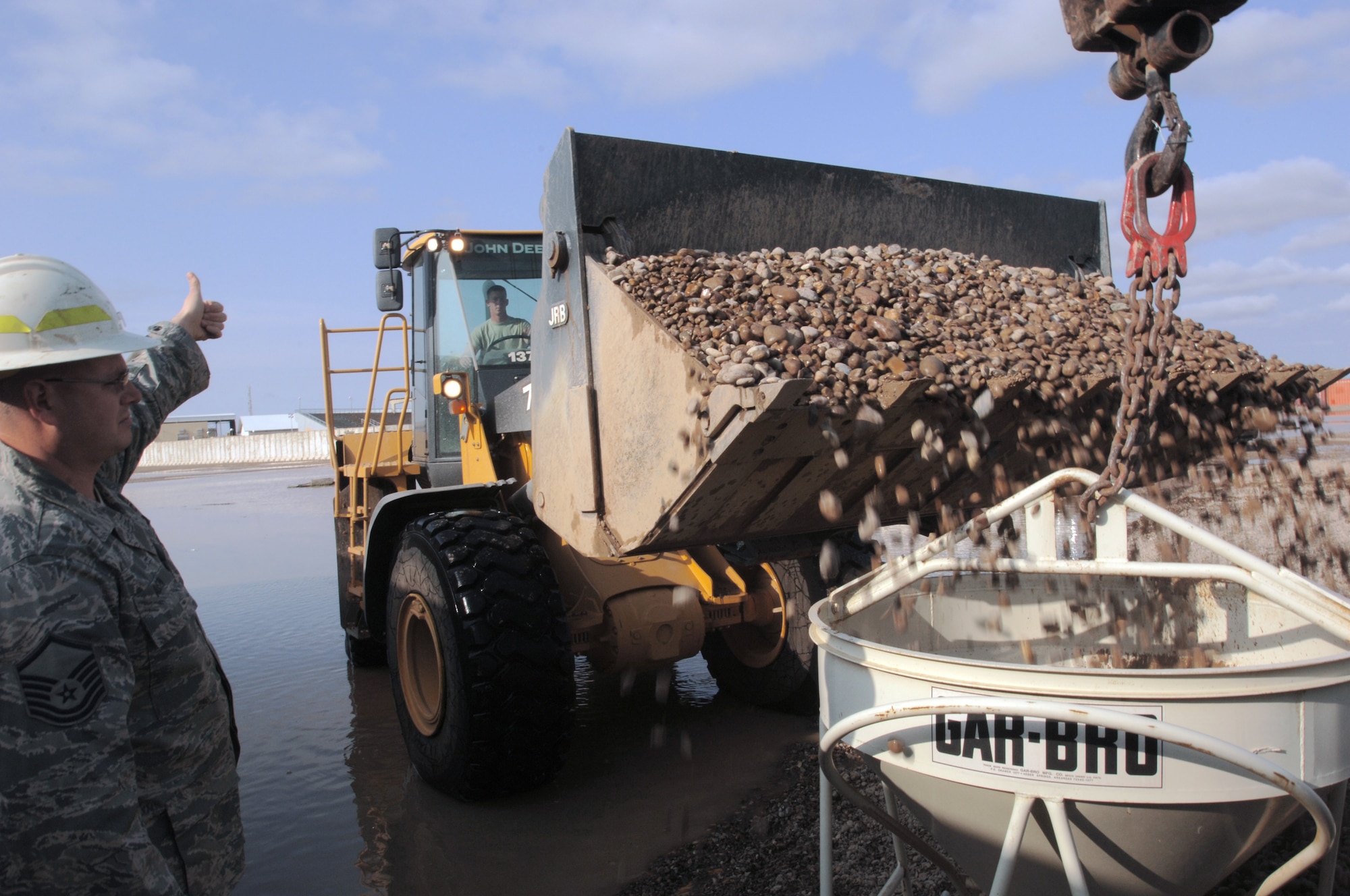 Master Sgt. Richard Winter signals a front-end loader to dump a load of rock into a concrete bucket Oct. 25 at Joint Base Balad, Iraq. The bucket will be moved by crane into low areas flooded with water. Sergeant Winter, an electrical systems craftsman with the 332nd Expeditionary Civil Engineer Squadron, is deployed from McChord Air Force Base, Wash. His hometown is Pittsburgh. (U.S. Air Force photo/Tech. Sgt. Erik Gudmundson) 