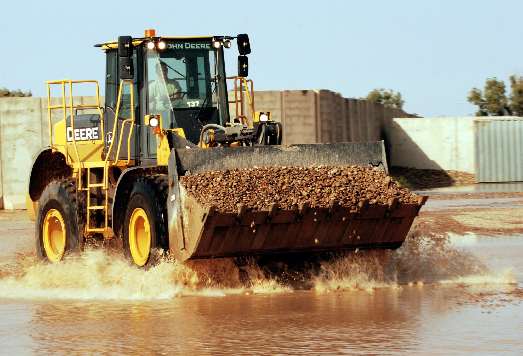 A front-end loader plows through a flooded area with a load of rock to build up low areas Oct. 25 at Joint Base Balad, Iraq. Because rain is infrequent in Iraq, when it does rain, the hardened ground soaks up little water. (U.S. Air Force photo/Tech. Sgt. Erik Gudmundson) 