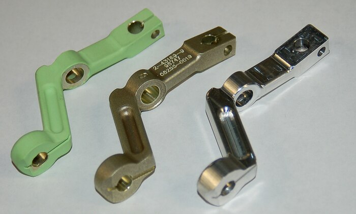 Three steps in the manufacturing process of T-38 aileron levers are shown as the part is first custom cut, right; numbered and textured, center; and finally painted green and shipped to the customer. (U.S. Air Force photo by Bill Orndorff)