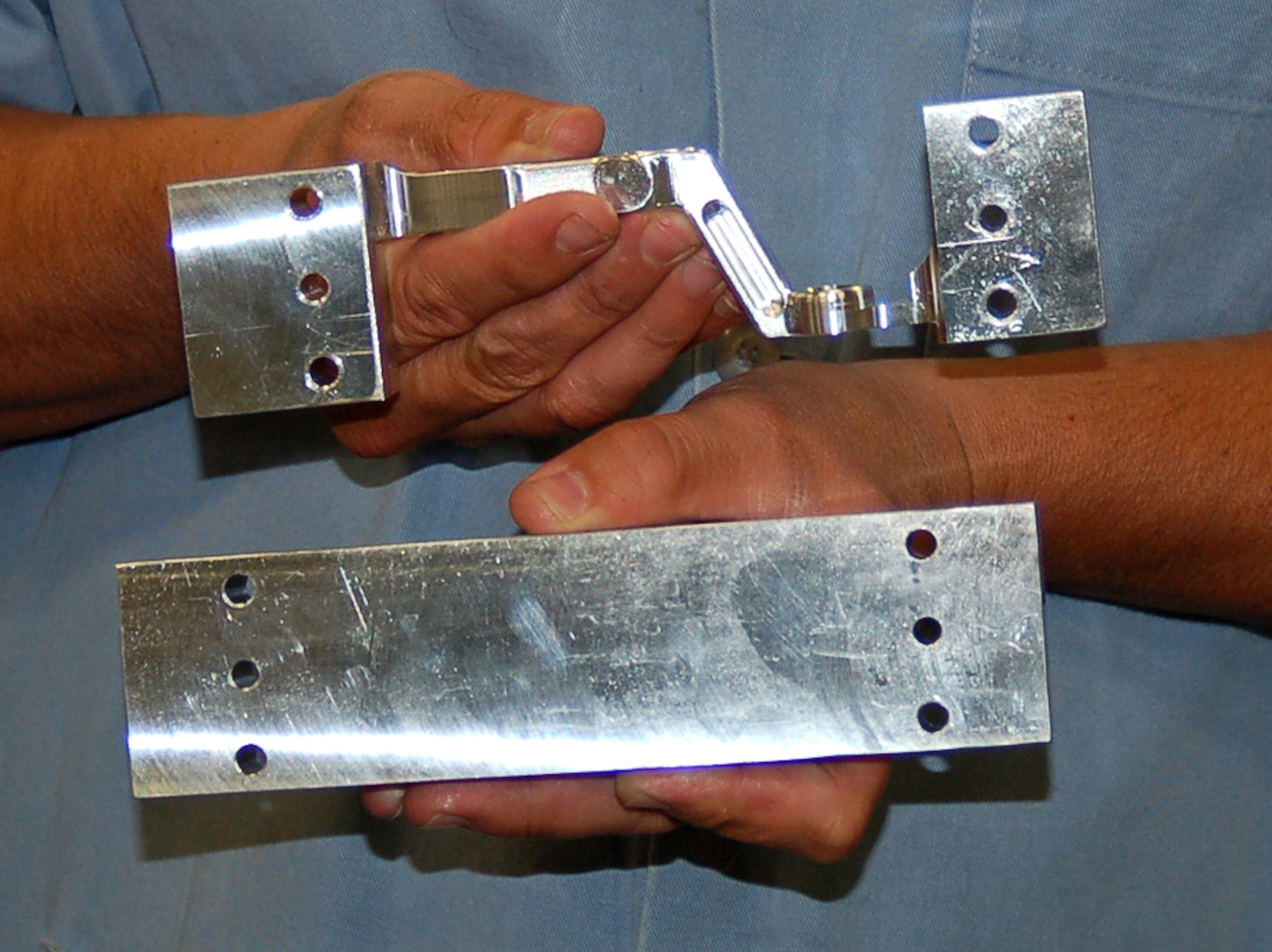 A newly milled T-38 aileron lever is compared to the original block of aluminum. The end pieces are eventually removed in the five-step manufacturing process. The New Manufacturing and Repair Division of the 532nd Commodities Maintenance Squadron milled more than 1,000 levers for the Air Force's fleet of T-38s. (U.S. Air Force photo by Bill Orndorff)